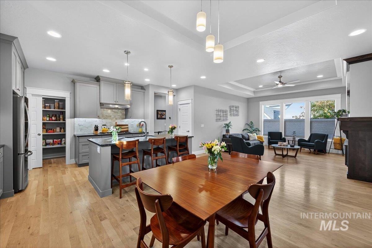 Dining area featuring a tray ceiling, light wood-style flooring, recessed lighting, and a ceiling fan