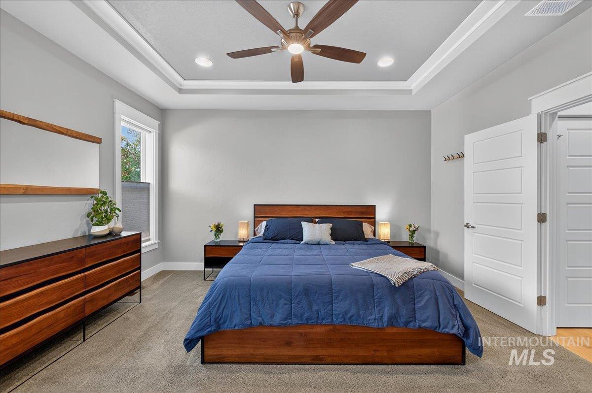Bedroom featuring ceiling fan, a raised ceiling, recessed lighting, and light carpet