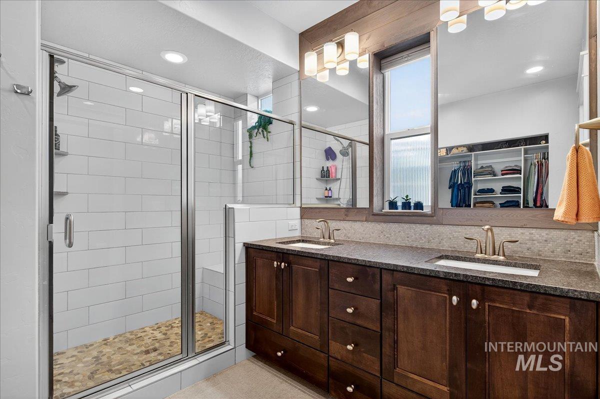 Bathroom with a stall shower, a walk in closet, double vanity, and recessed lighting