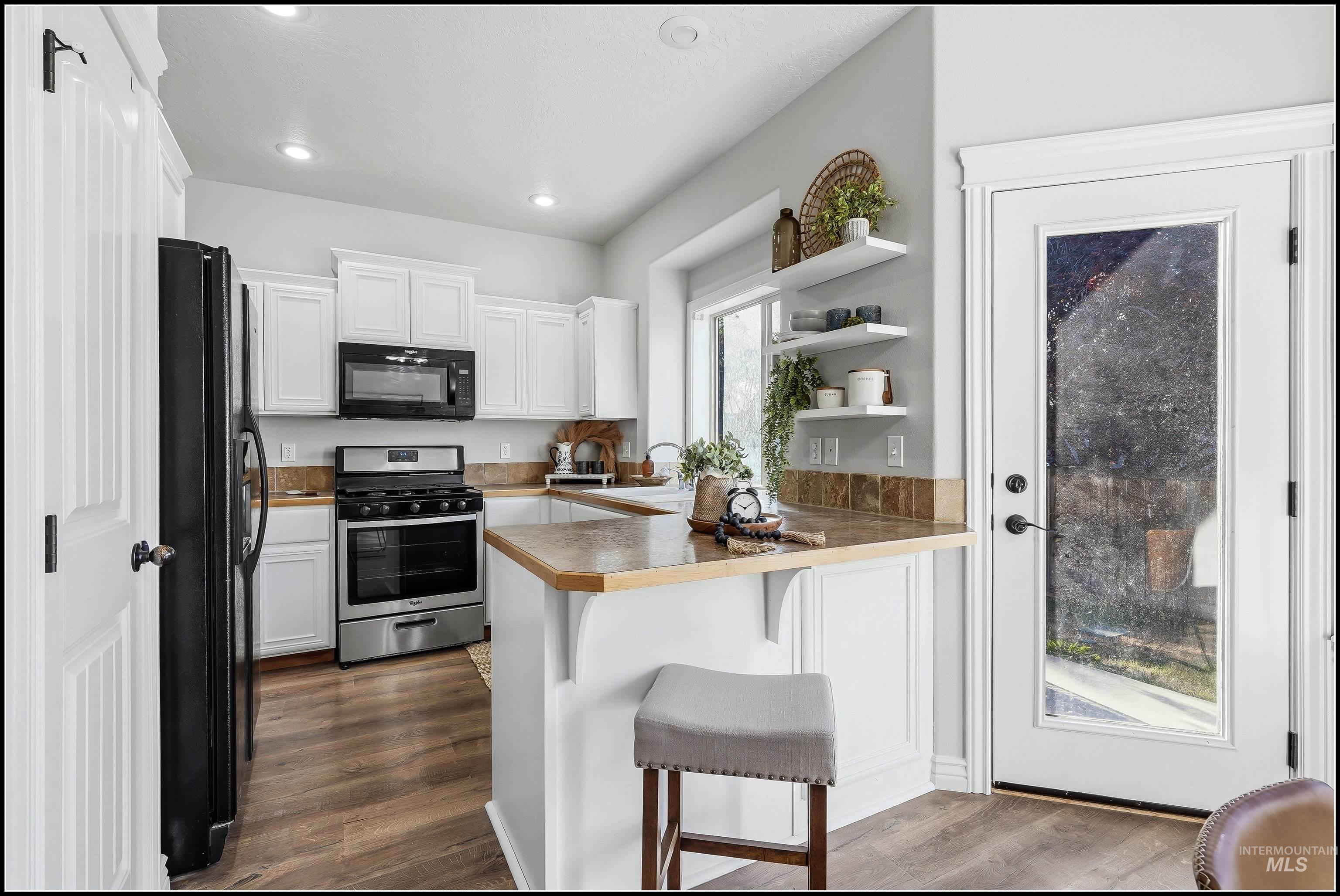 Kitchen featuring wood-finish flooring, white cabinetry, and a peninsula with countertop seating