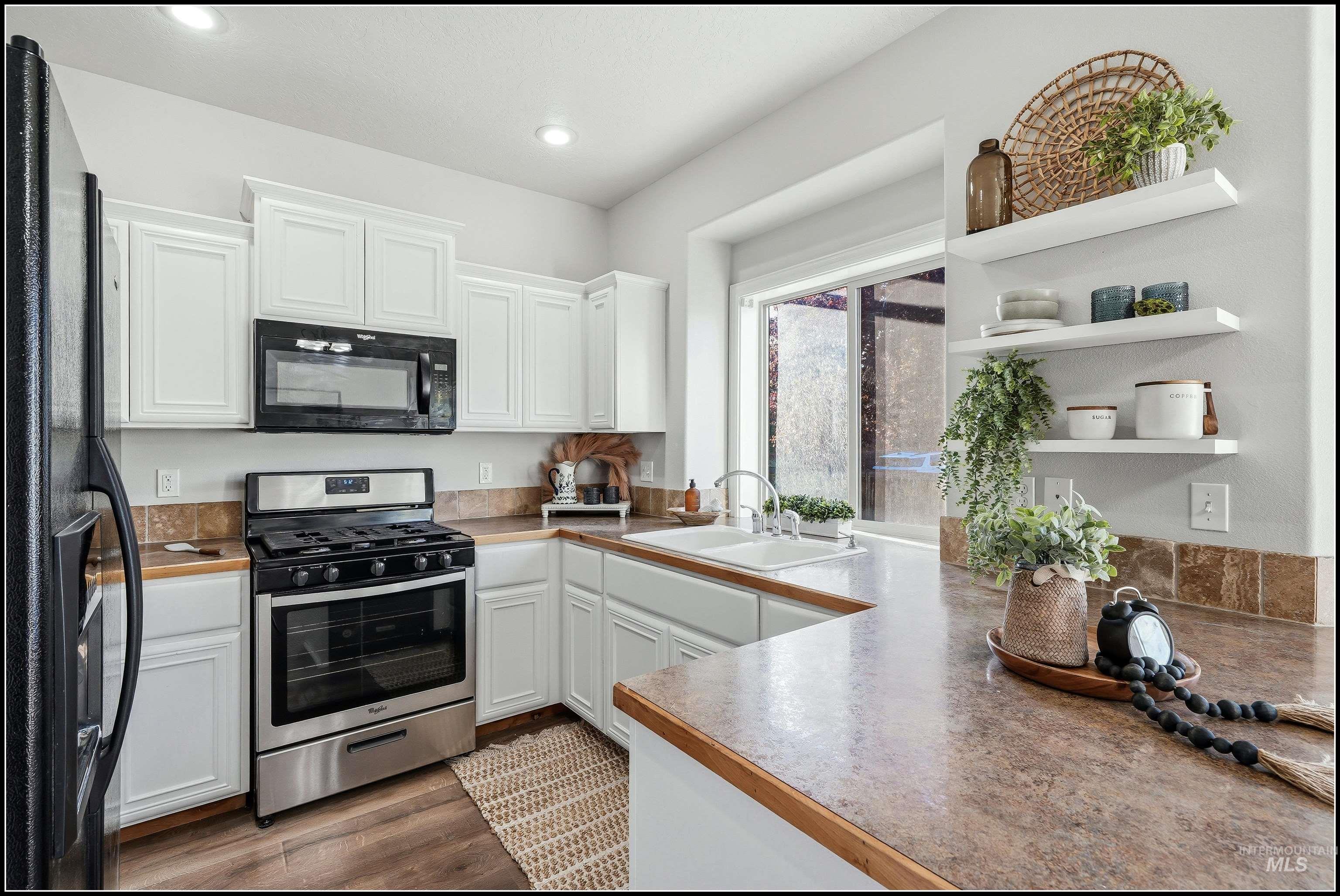 Bright kitchen featuring white cabinetry, and a 5-burner stainless steel gas range