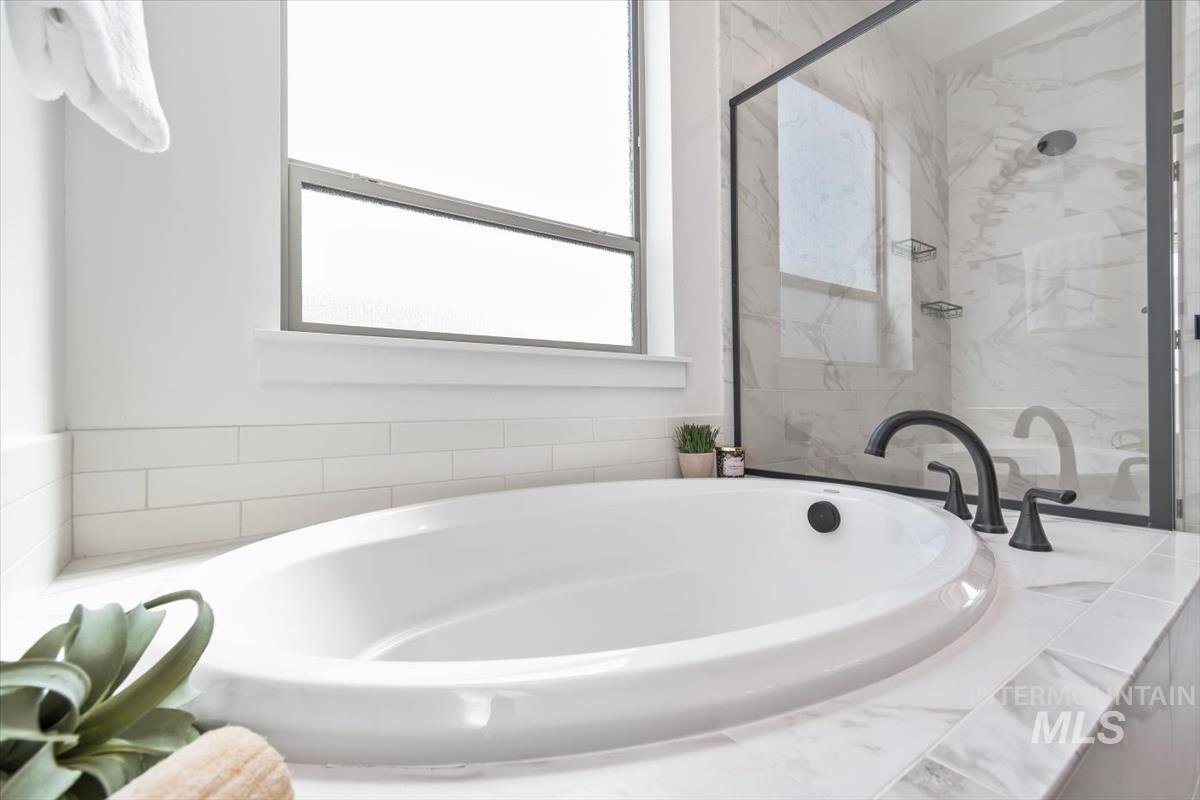 Bathroom with a garden tub and a marble finish shower