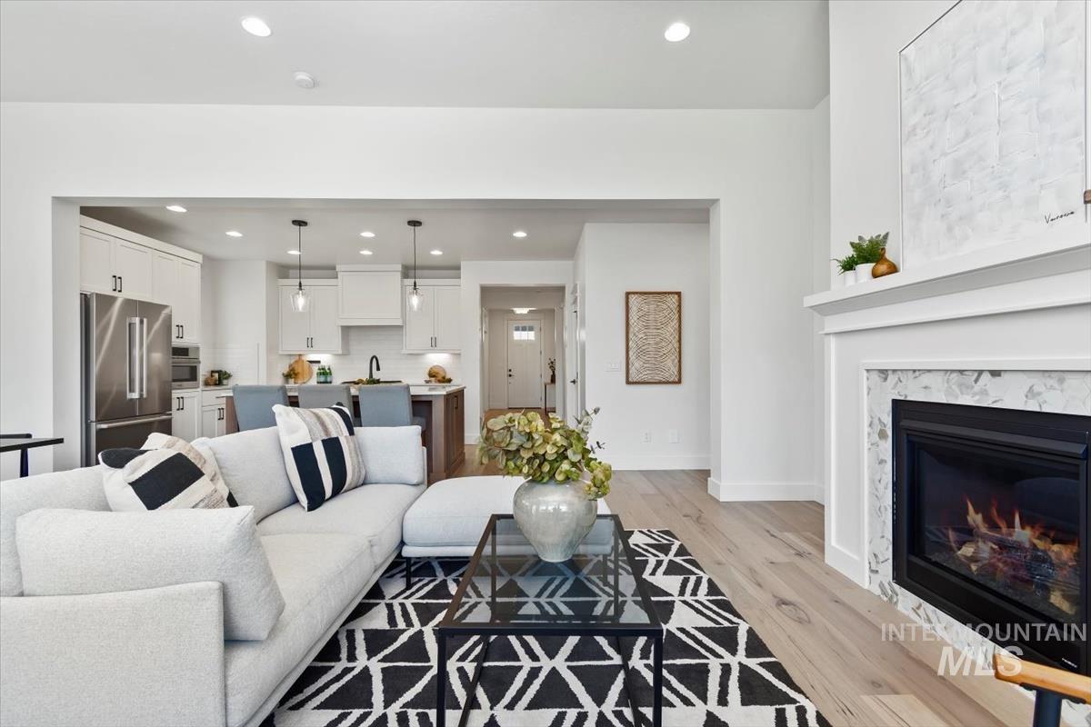 Living room featuring recessed lighting, light wood-style floors, and a high end fireplace