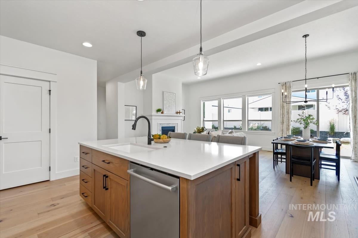 Kitchen with stainless steel dishwasher, recessed lighting, light wood finished floors, a fireplace, and hanging light fixtures