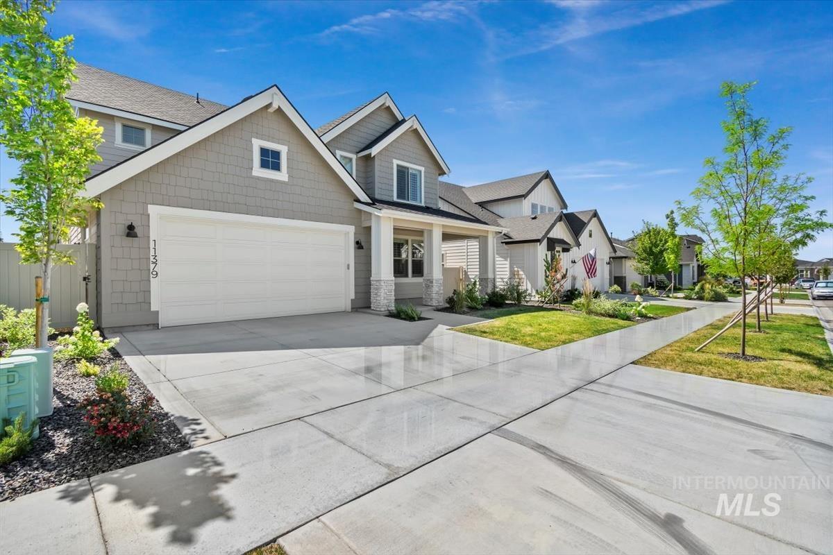 Craftsman-style home featuring a residential view, concrete driveway, a shingled roof, stone siding, and a garage