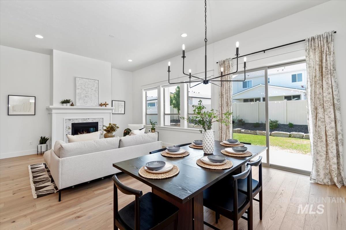 Dining area with light wood-type flooring, a glass covered fireplace, recessed lighting, and a chandelier