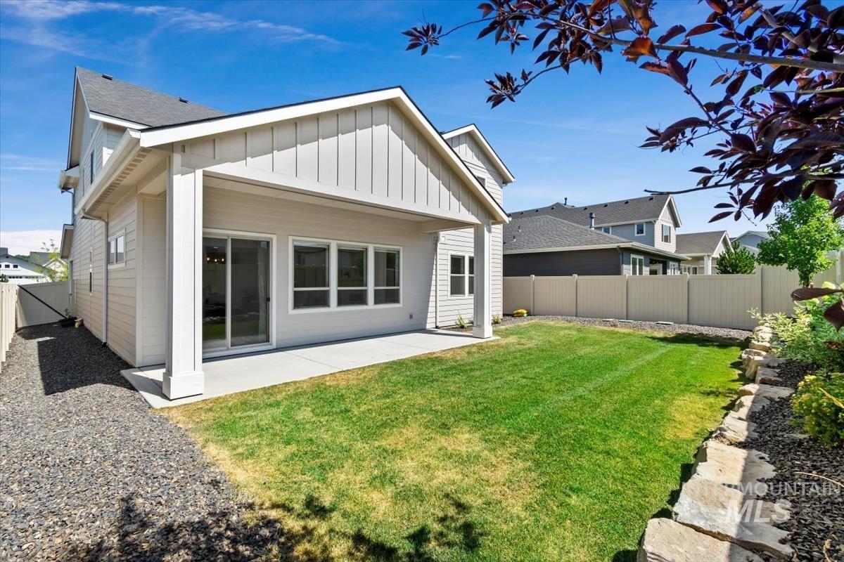 Back of house featuring board and batten siding, a patio, a fenced backyard, and a shingled roof