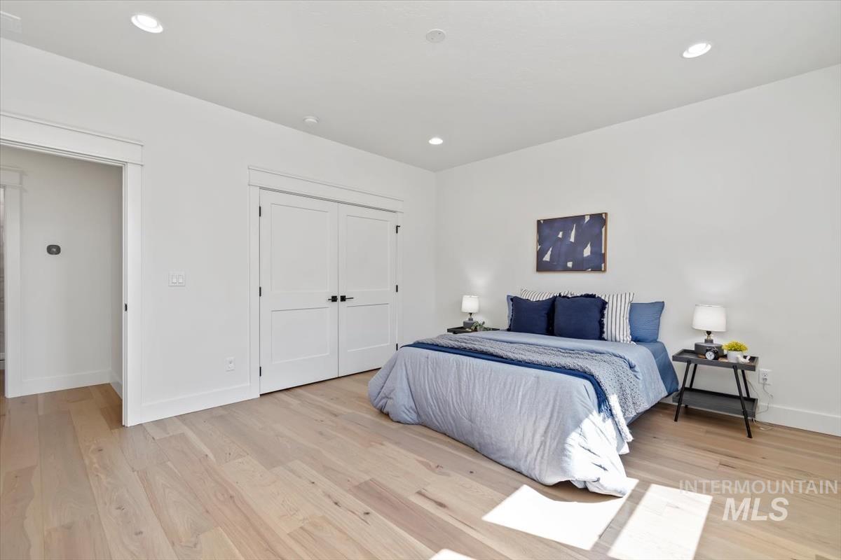 Bedroom with light wood-type flooring, recessed lighting, and a closet
