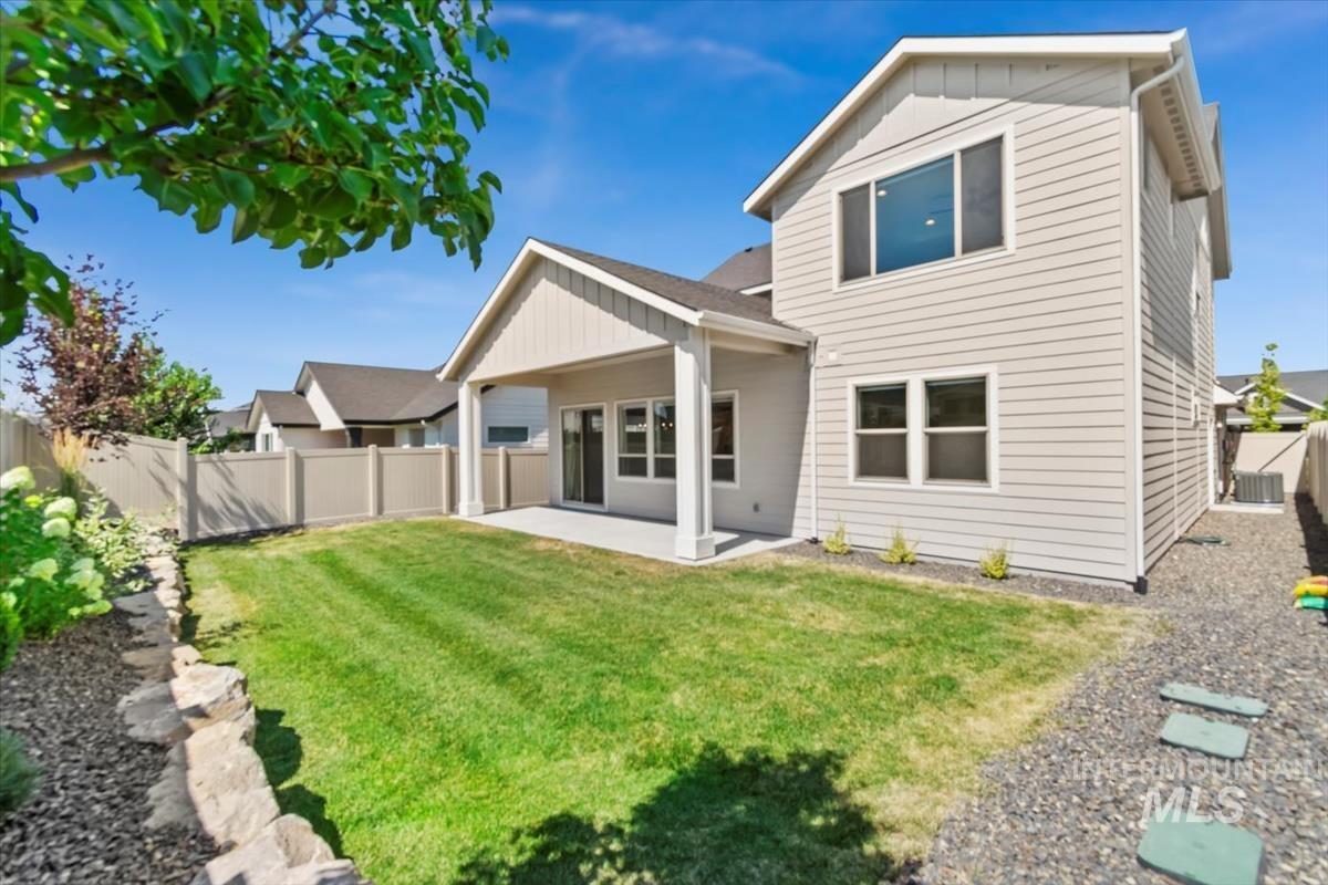 Rear view of house with board and batten siding, a patio, and a fenced backyard