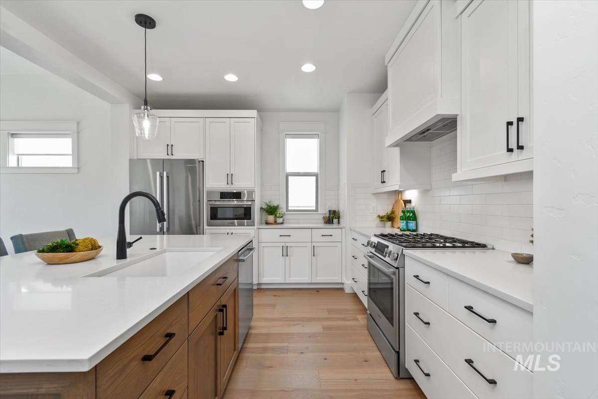 Kitchen with stainless steel appliances, recessed lighting, light wood finished floors, white cabinets, and light countertops