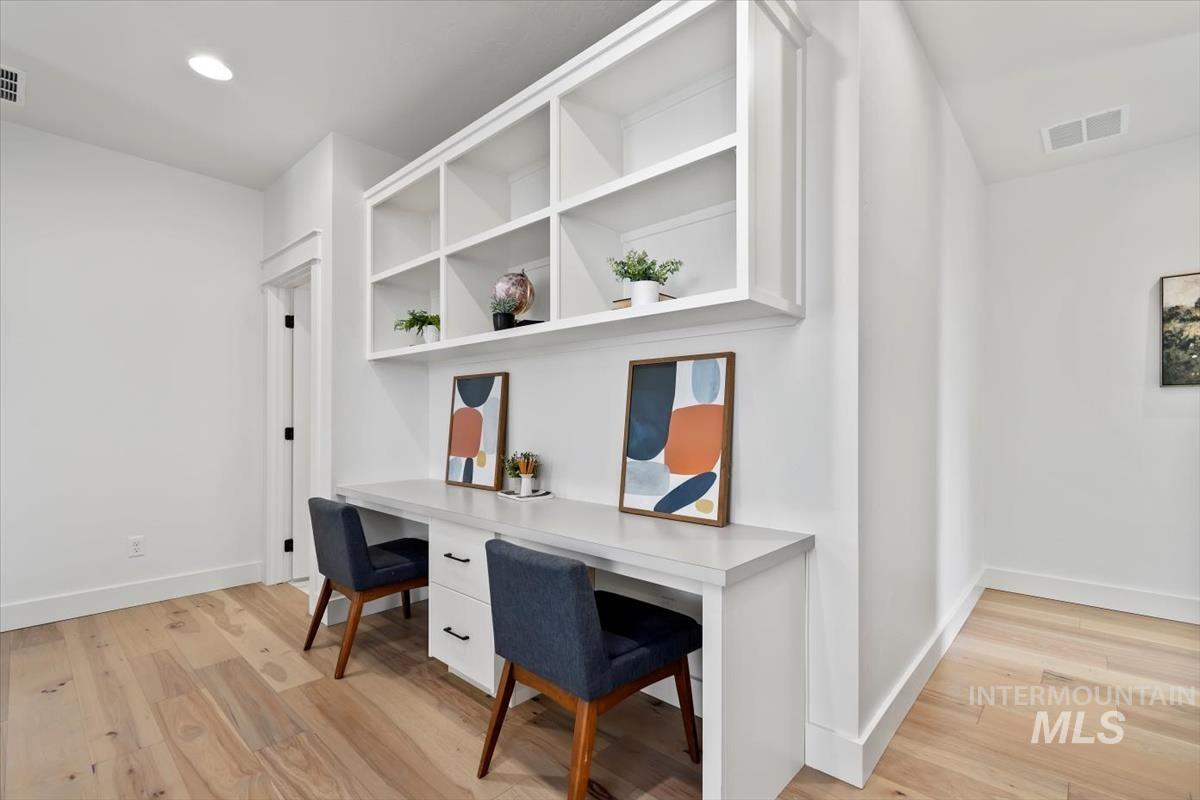 Home office with light wood-style flooring and recessed lighting