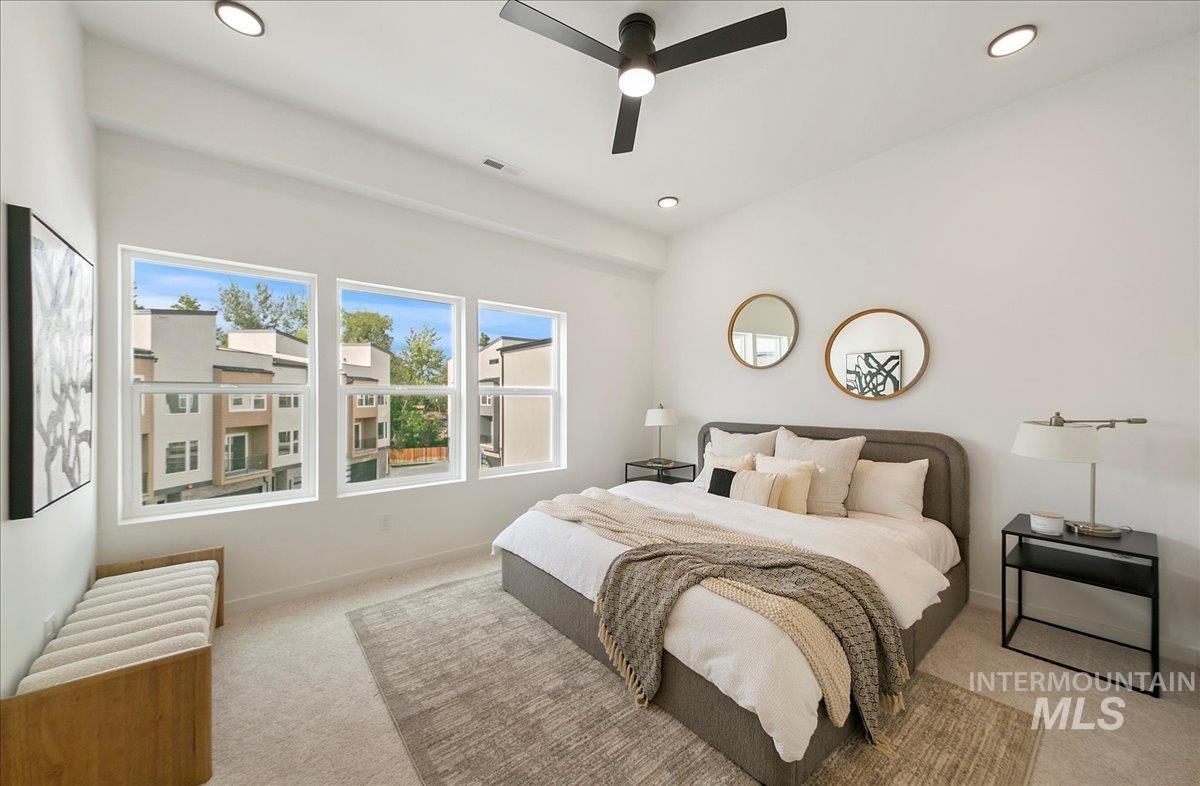 Carpeted bedroom with multiple windows and ceiling fan