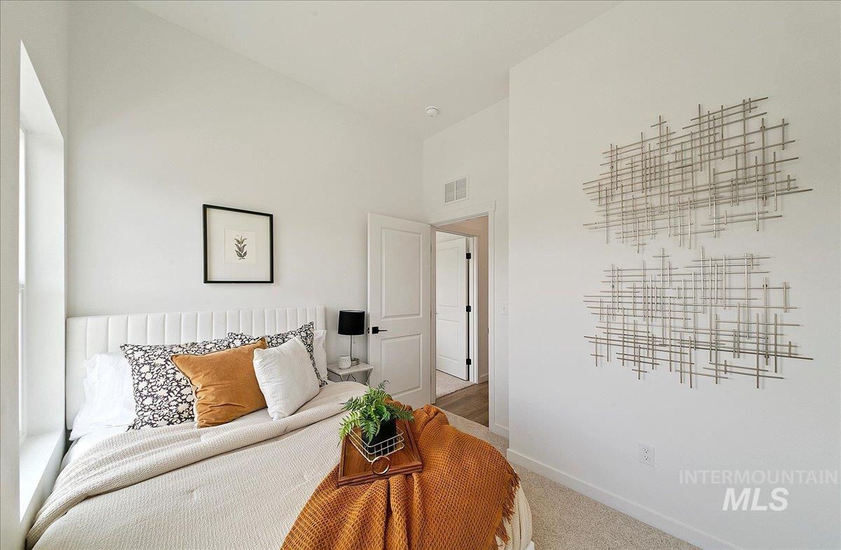 Carpeted bedroom with high vaulted ceiling and baseboards