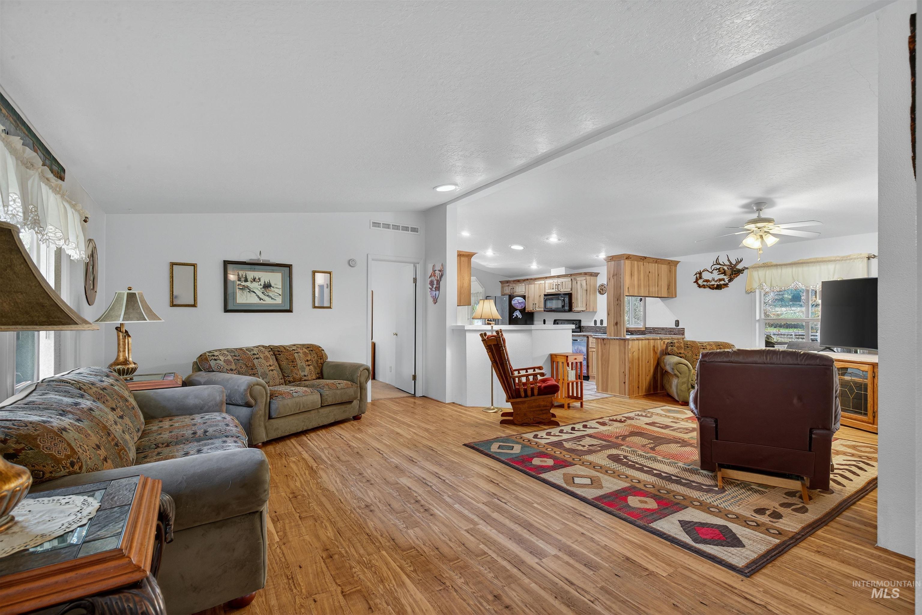 Living room featuring vaulted ceiling, light wood finished floors, and a ceiling fan