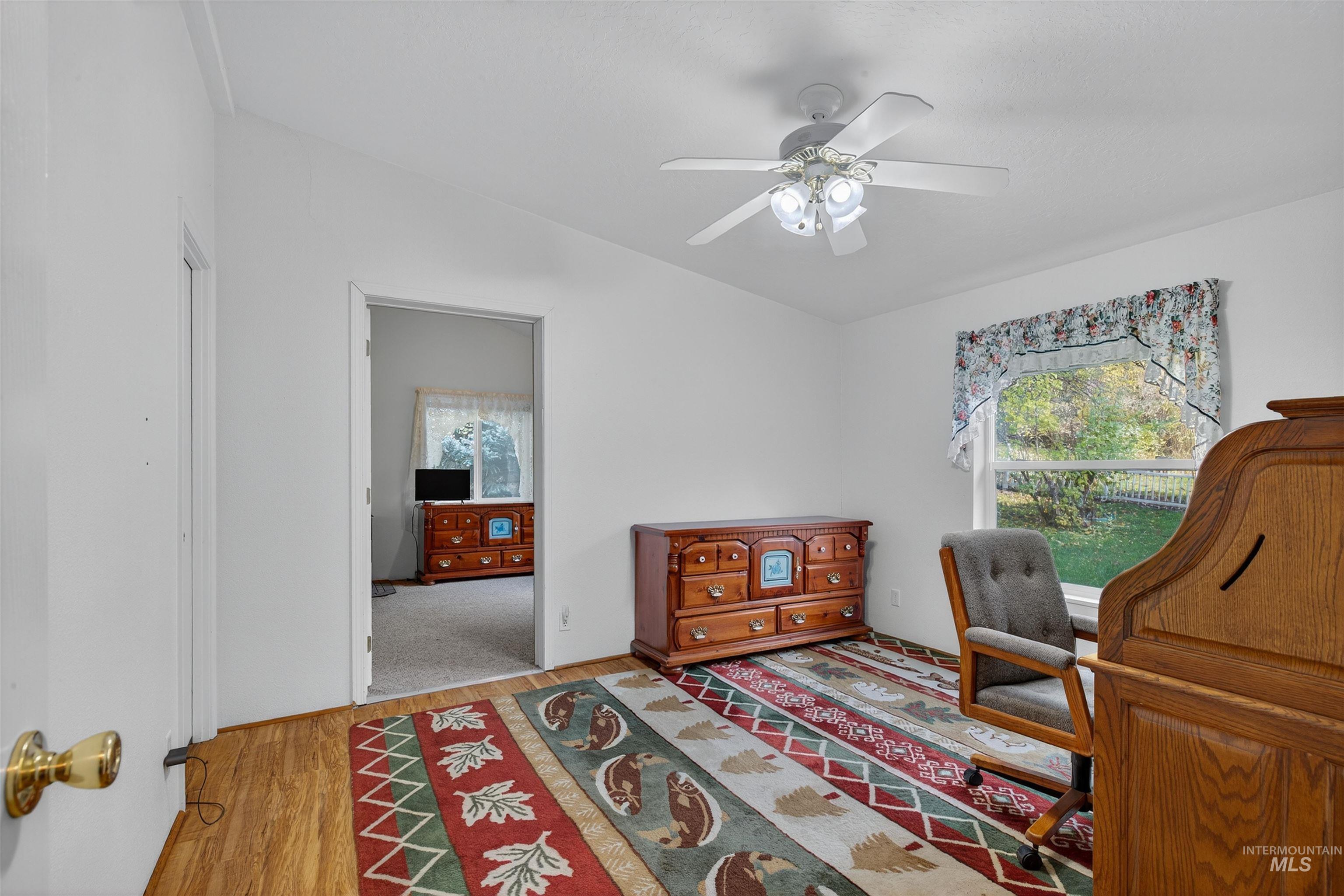 Office space featuring light wood finished floors, healthy amount of natural light, and a ceiling fan