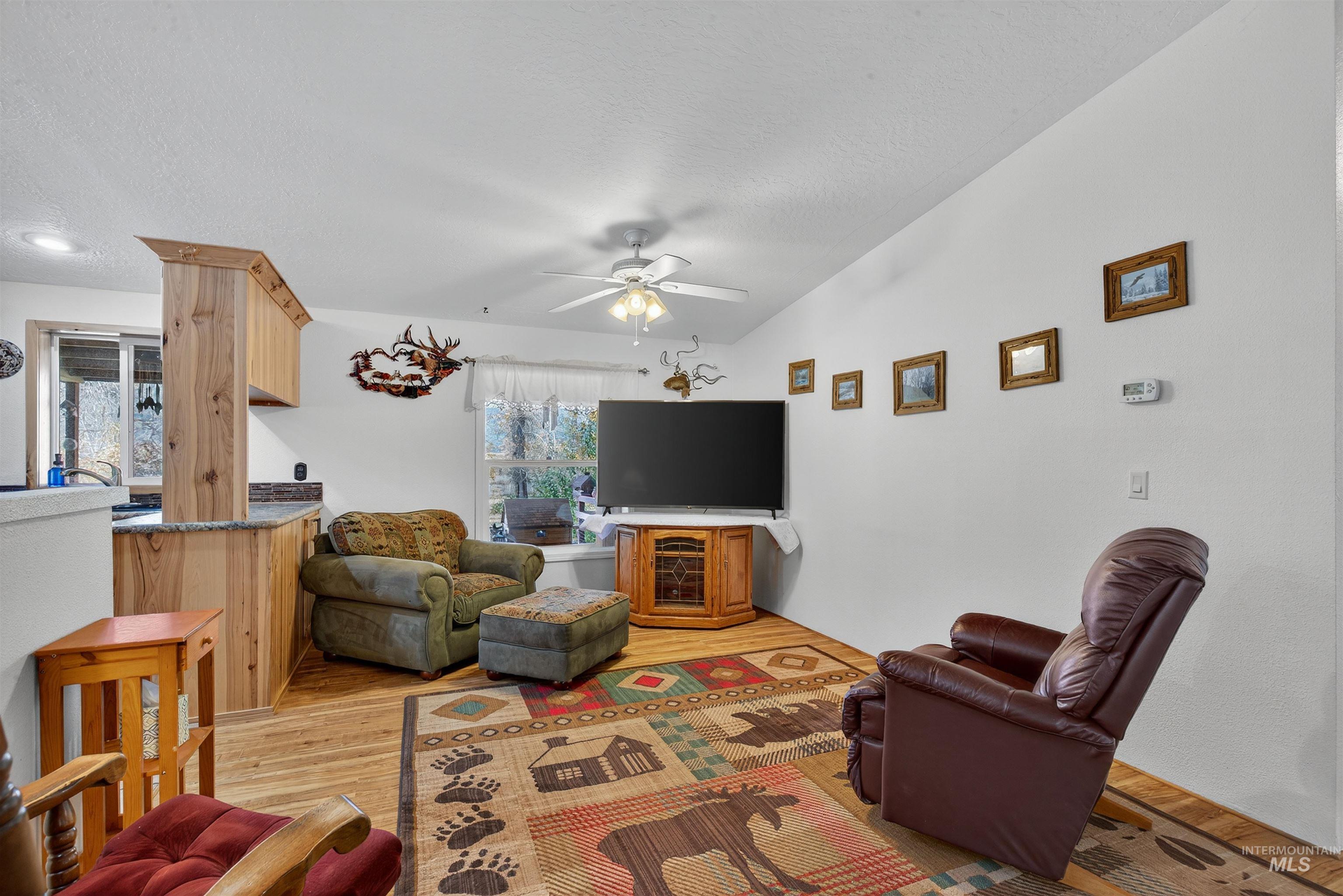 Living area with light wood-type flooring, ceiling fan, and a textured ceiling