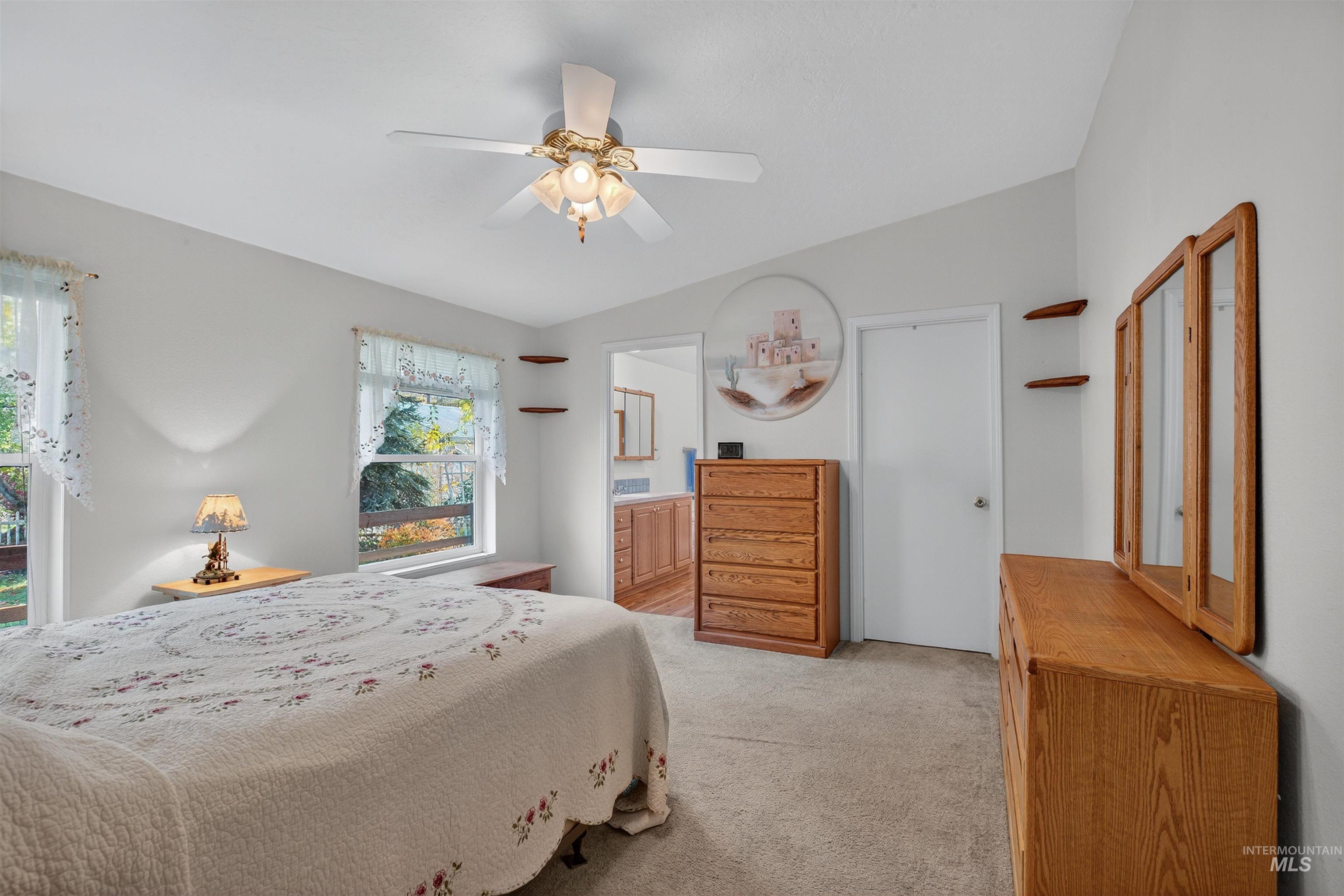 Bedroom featuring light colored carpet, ceiling fan, and connected bathroom