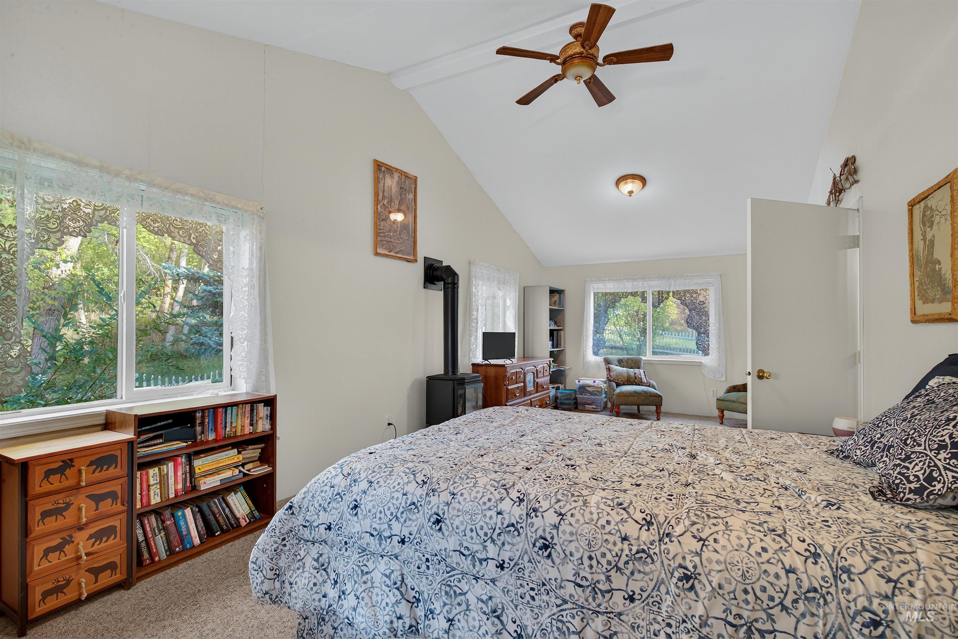 Carpeted bedroom with beam ceiling, a ceiling fan, high vaulted ceiling, and a wood stove
