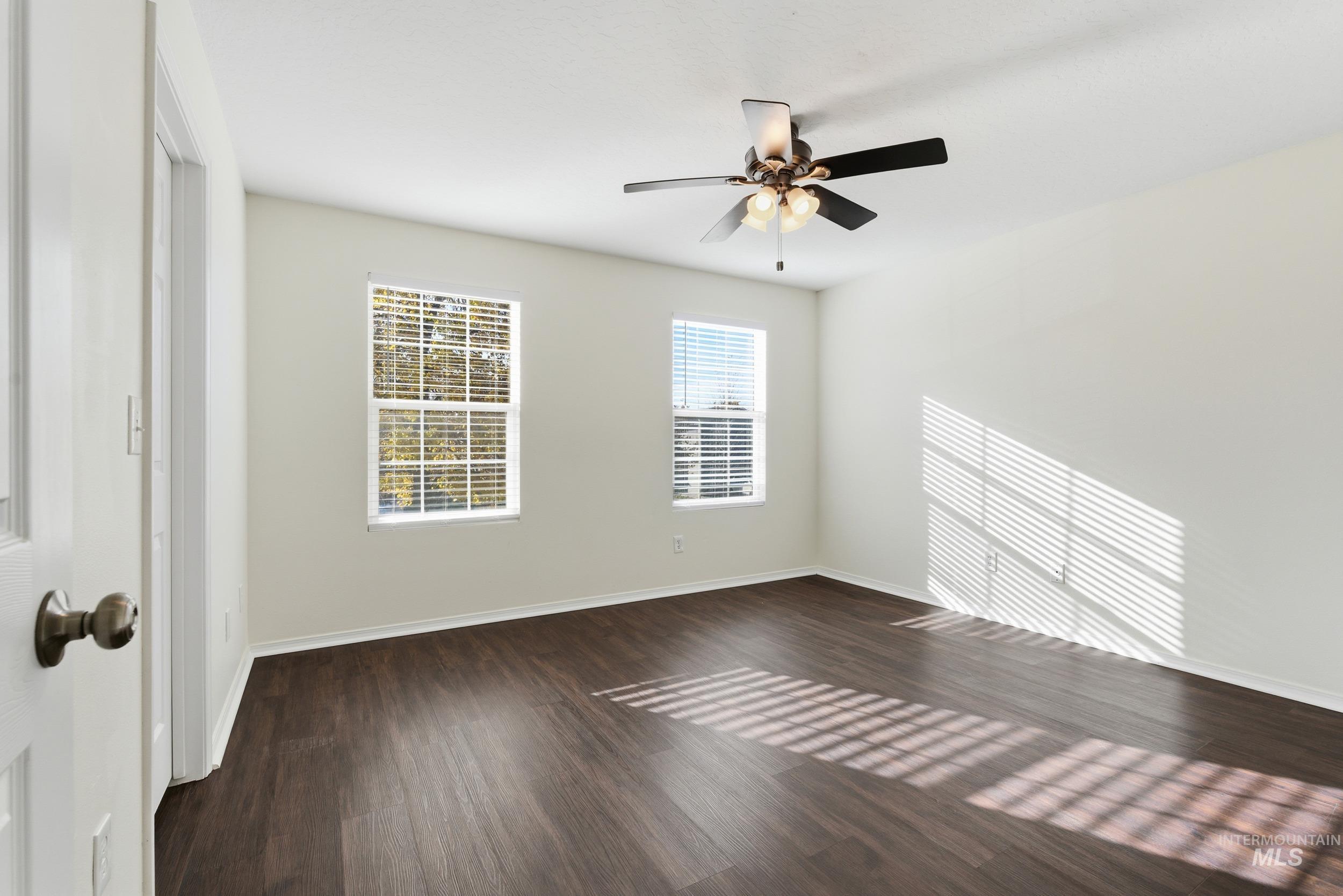 Unfurnished room featuring dark wood finished floors and ceiling fan