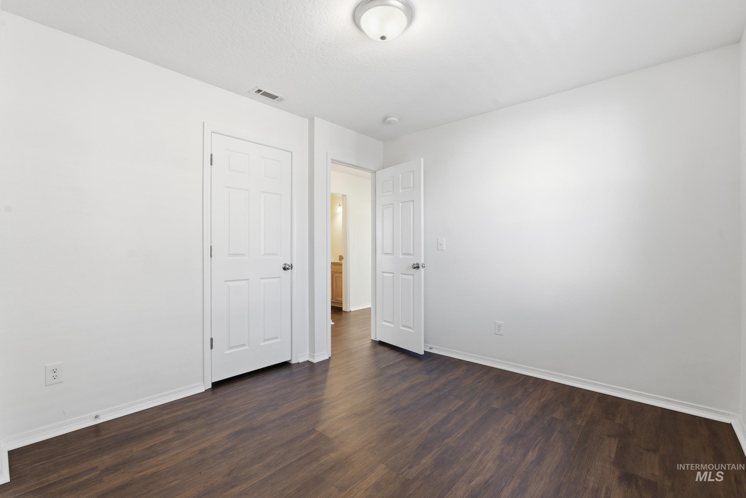 Unfurnished bedroom featuring dark wood-style flooring and baseboards