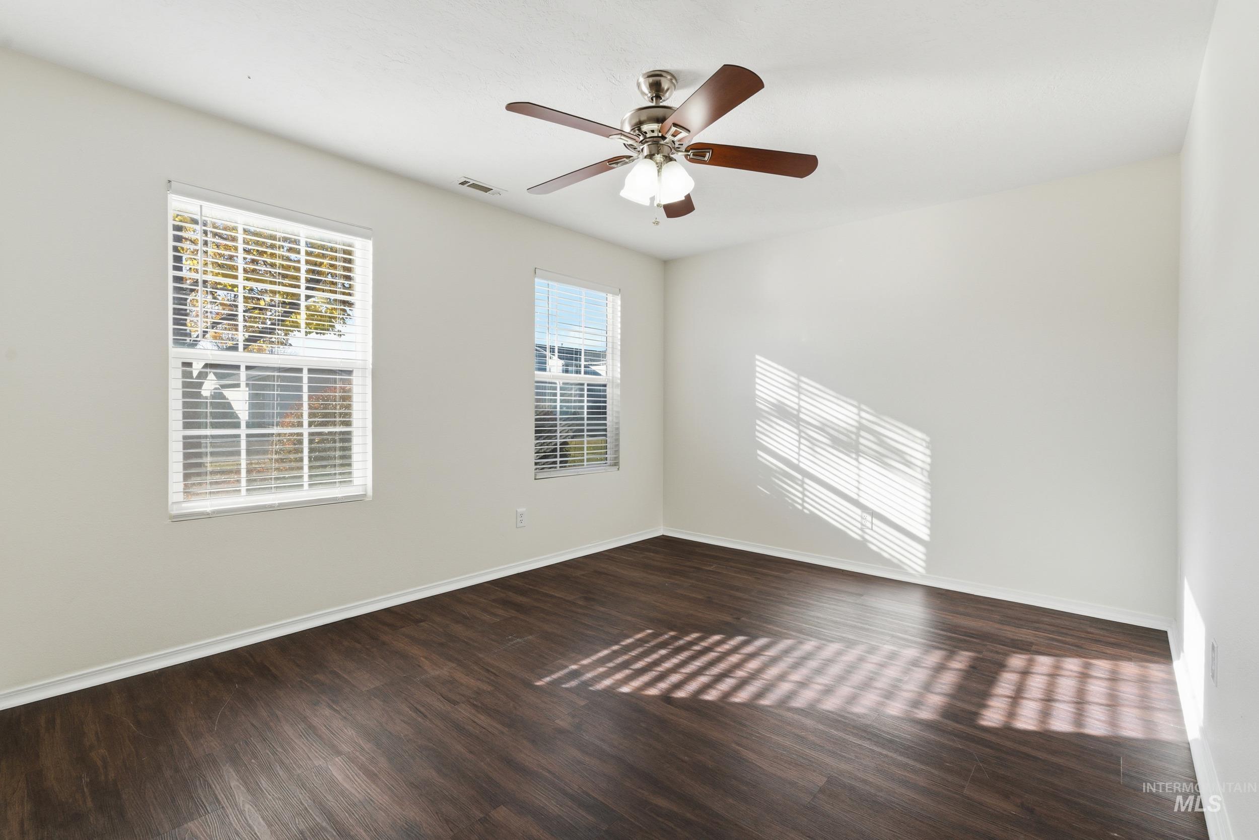 Unfurnished room featuring dark wood-type flooring and ceiling fan