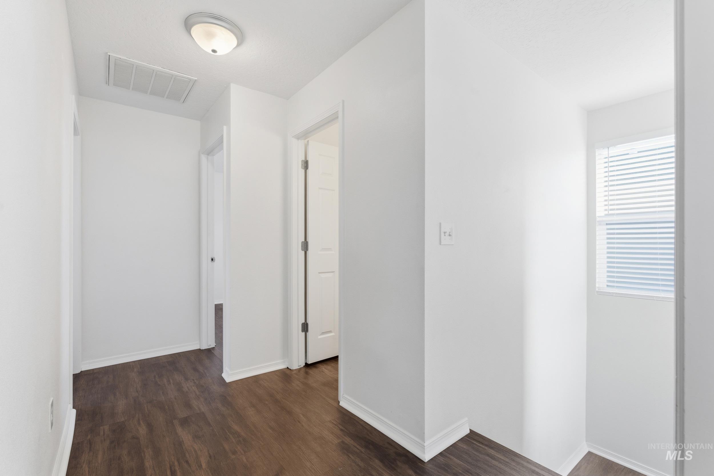 Hallway featuring baseboards and dark wood finished floors