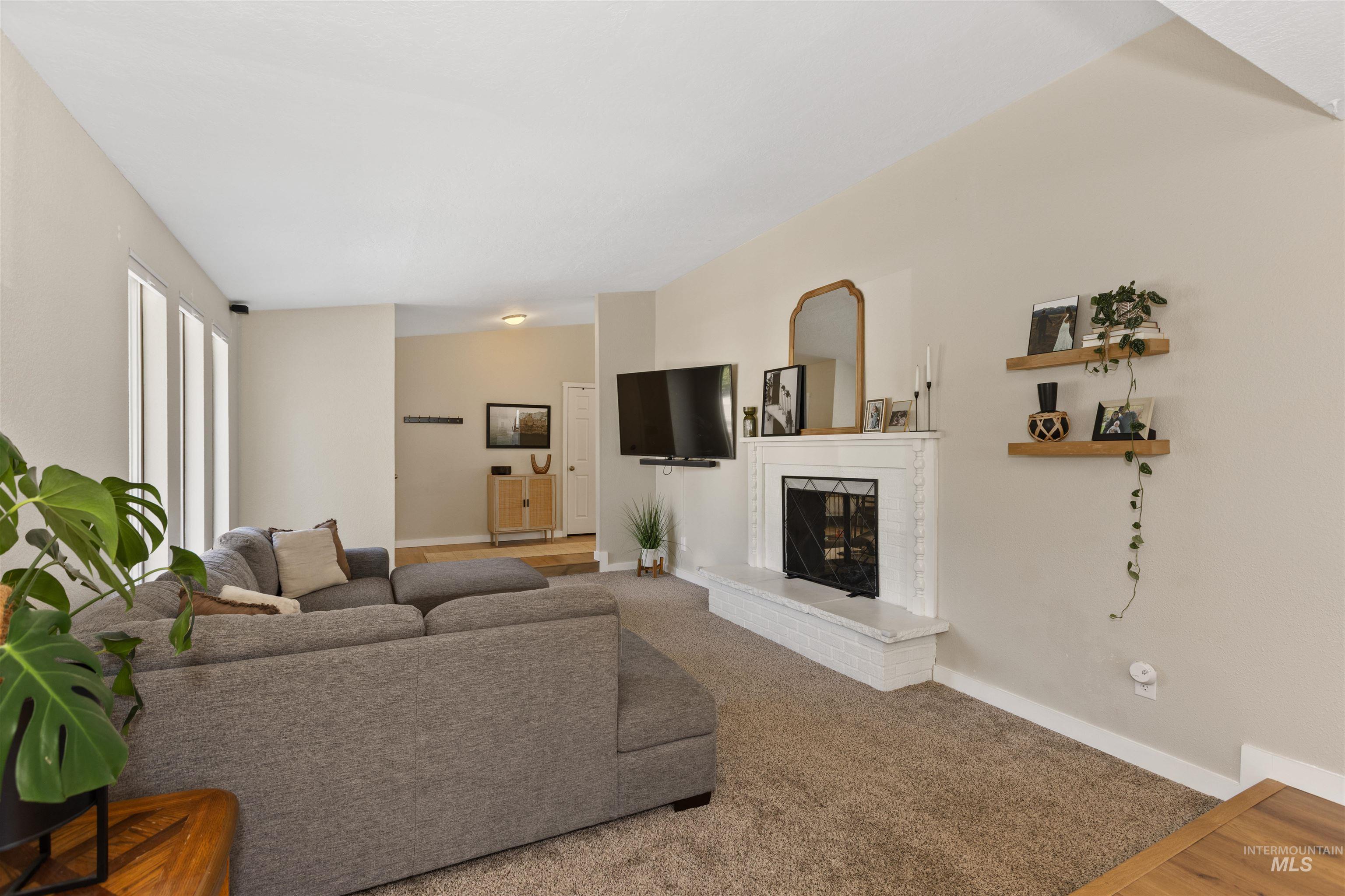 Carpeted living room with a brick fireplace and baseboards