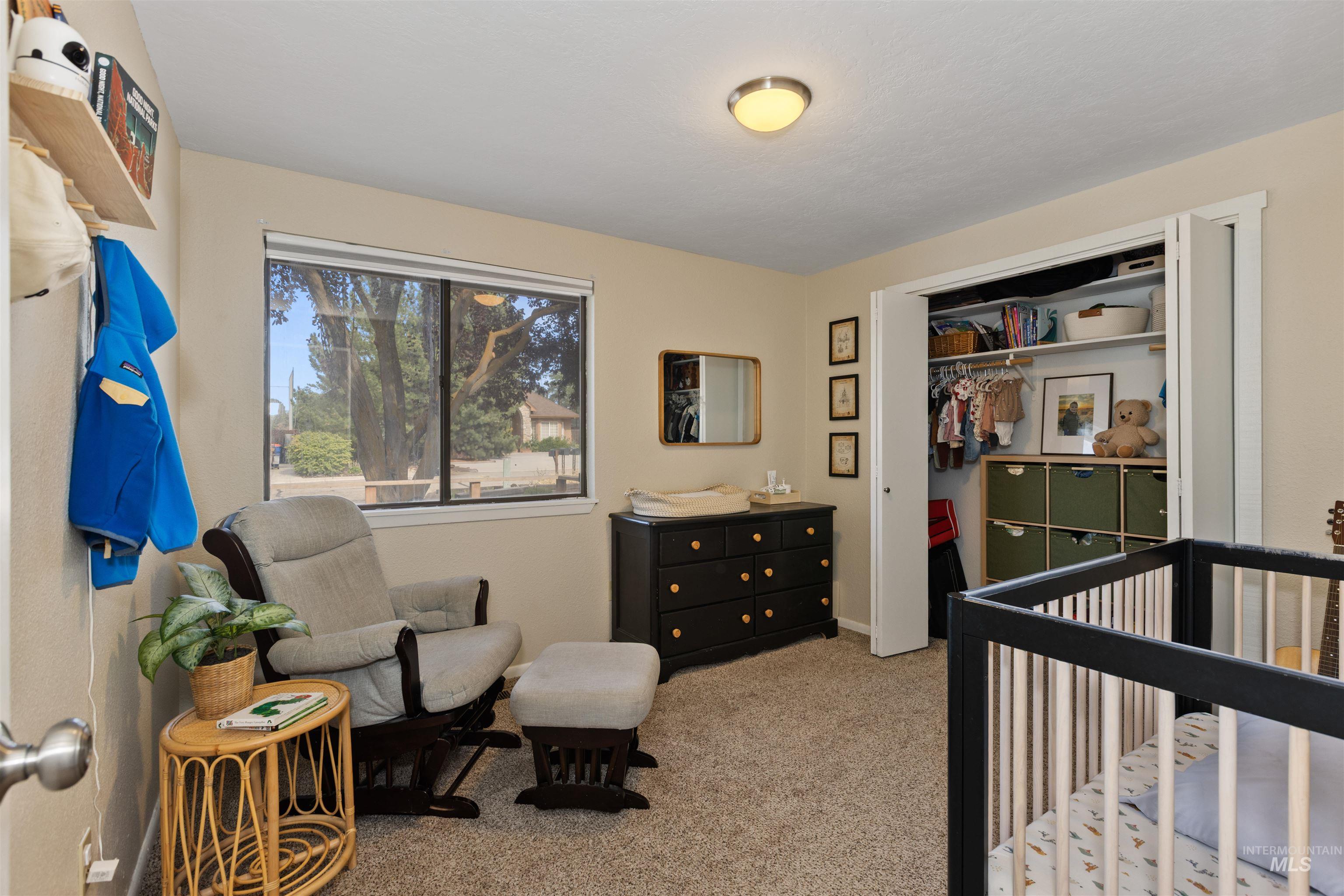 Carpeted bedroom with a nursery area and a closet