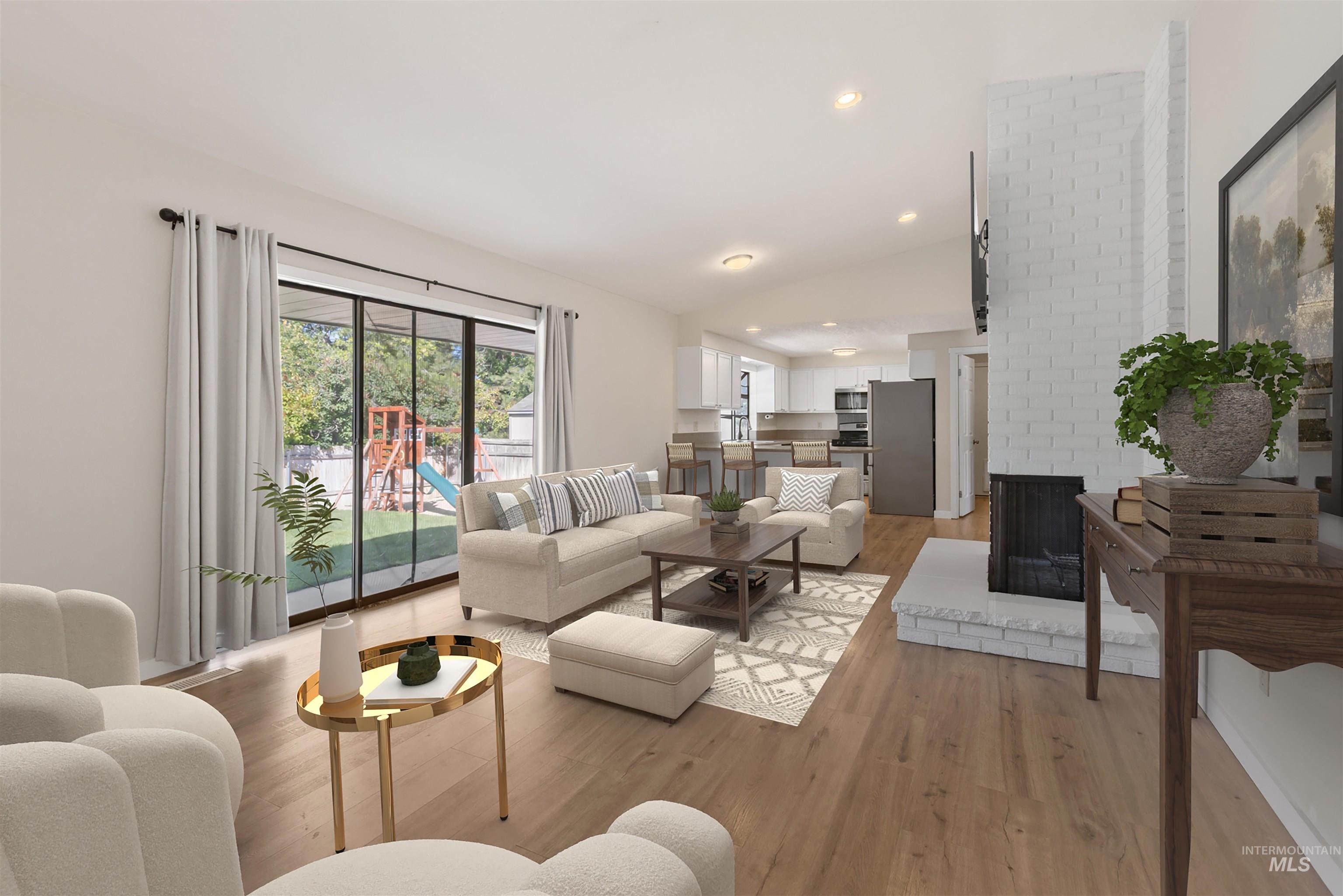 Living area featuring light wood-style flooring, a brick fireplace, lofted ceiling, and recessed lighting