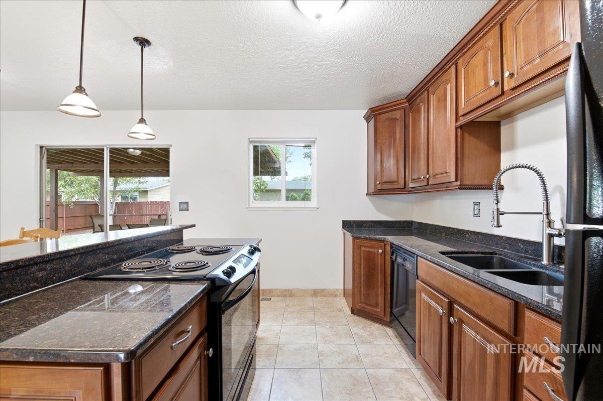 Kitchen featuring wood cabinetry, dark countertops, a built-in electric range, and a dual basin sink with a gooseneck faucet