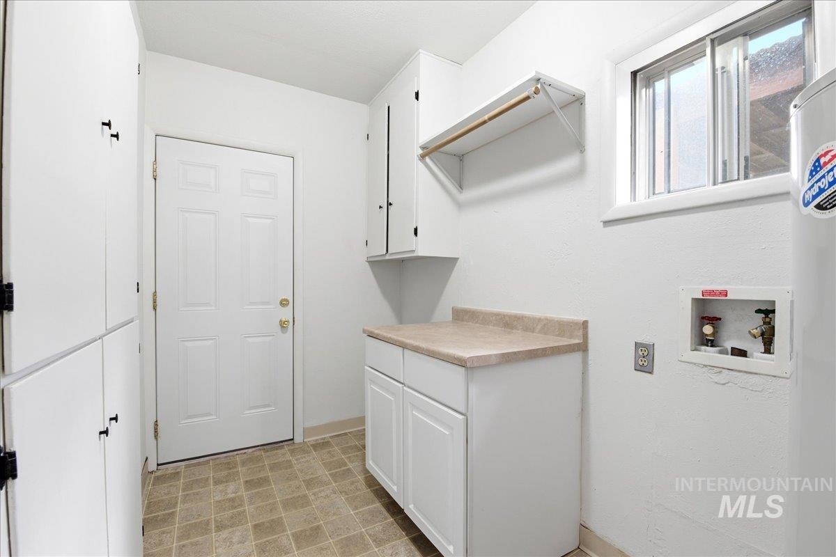 Spacious utility area featuring extensive white cabinetry, a built-in countertop, and a window for natural light