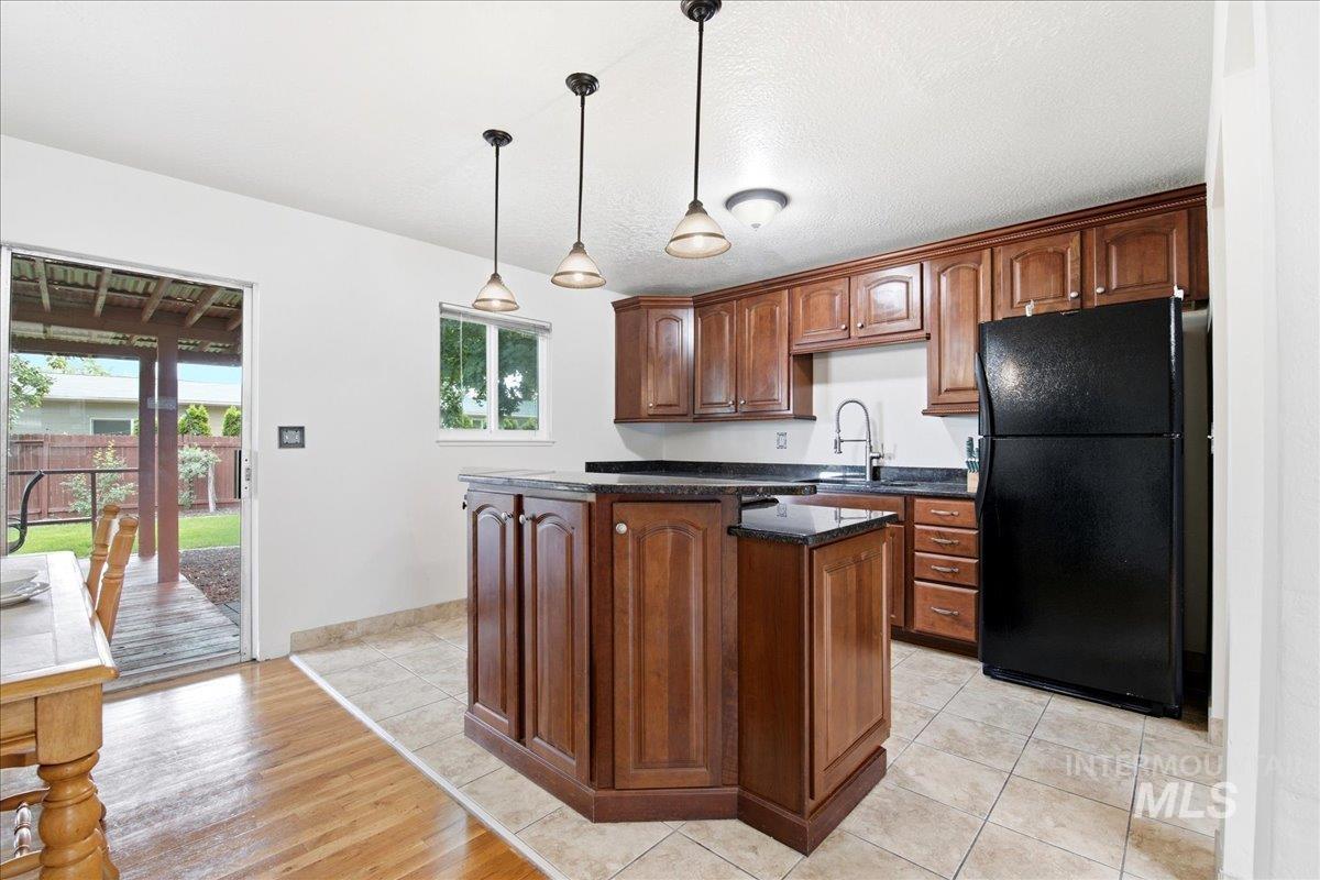 Kitchen featuring wood-finish cabinetry, dark countertops, and a black refrigerator