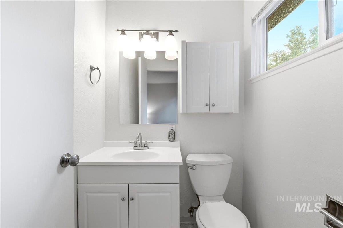 Bathroom featuring a white vanity with integrated sink, chrome faucet, and mirrored medicine cabinet
