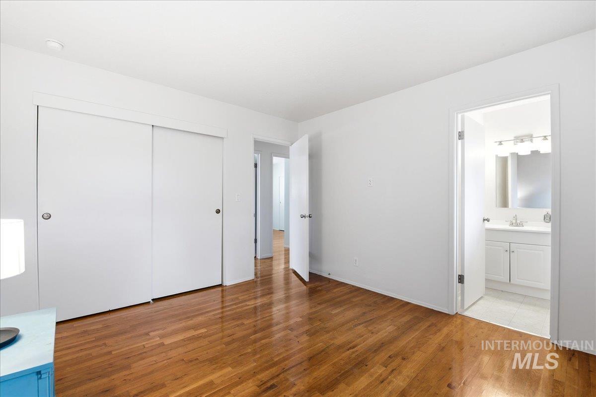Hardwood-finish flooring throughout, featuring a white sliding door closet, solid white walls, and a recessed ceiling light