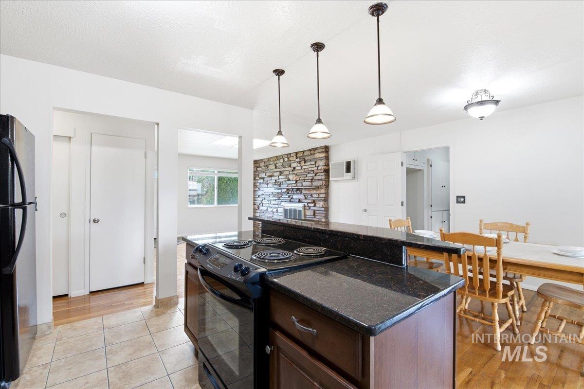 Kitchen island with a built-in electric range, dark stone countertops, and wood-finish cabinetry