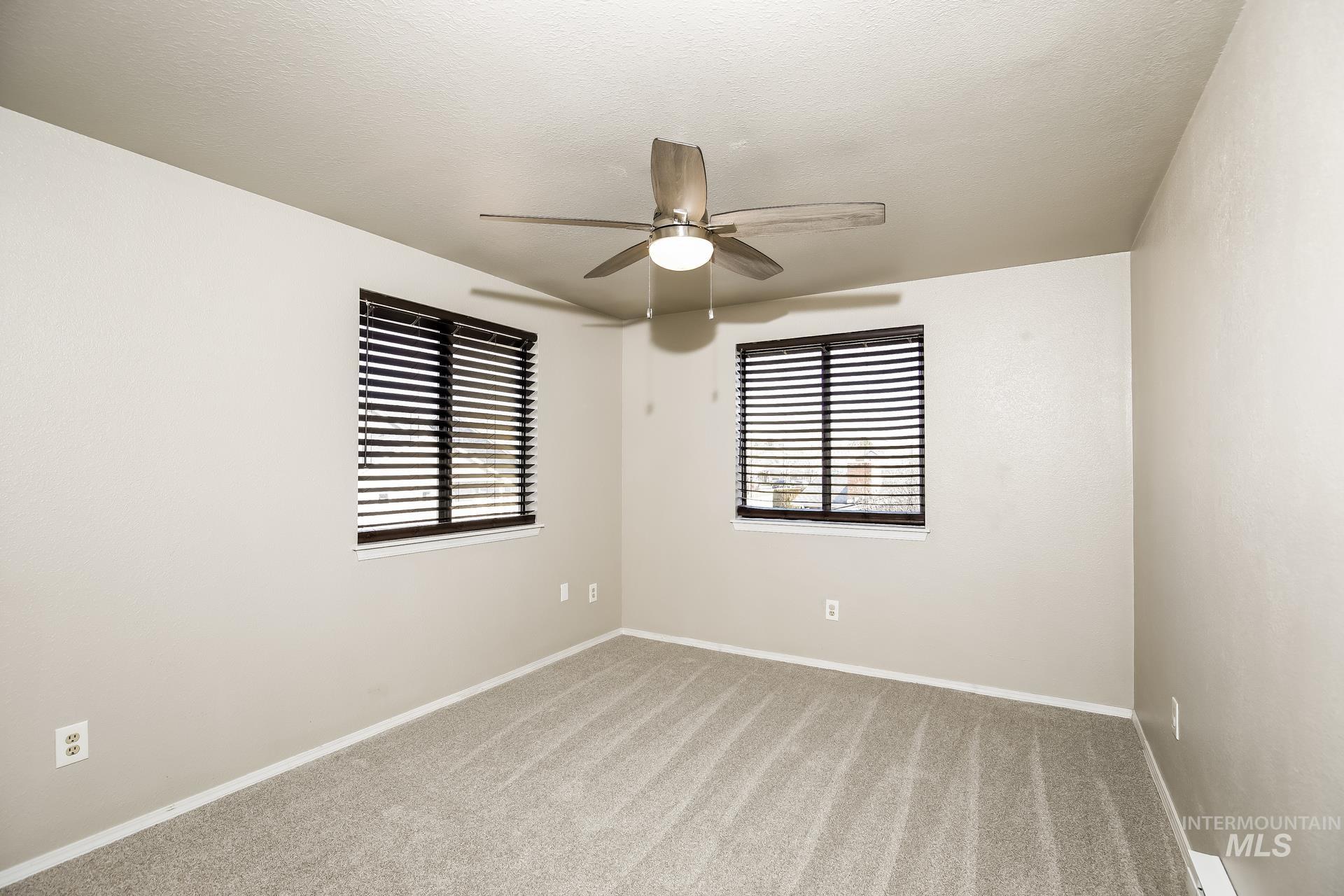 Carpeted empty room featuring baseboards and ceiling fan
