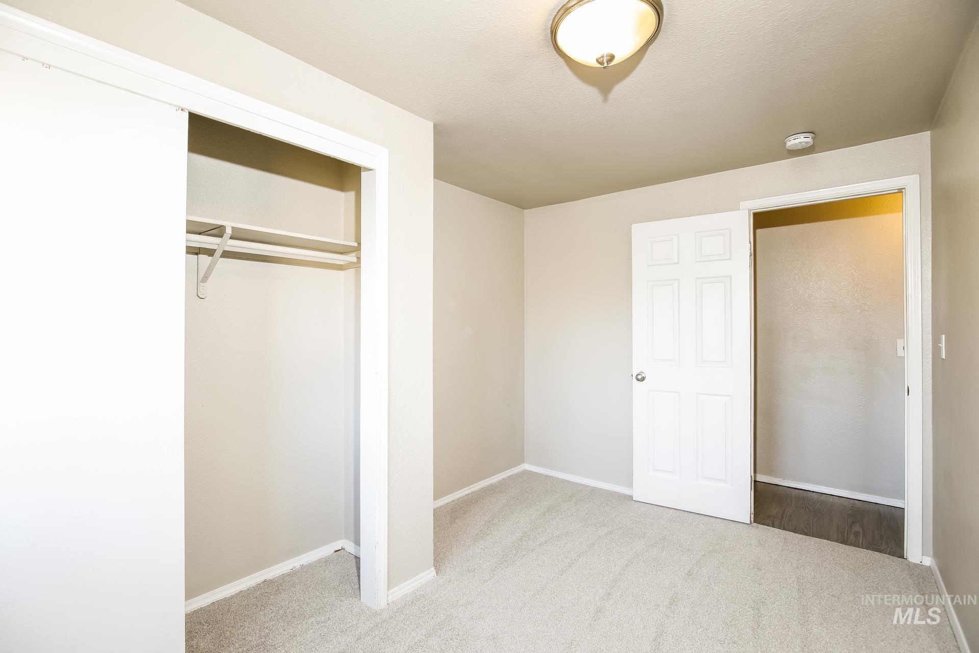 Unfurnished bedroom with light carpet and a closet