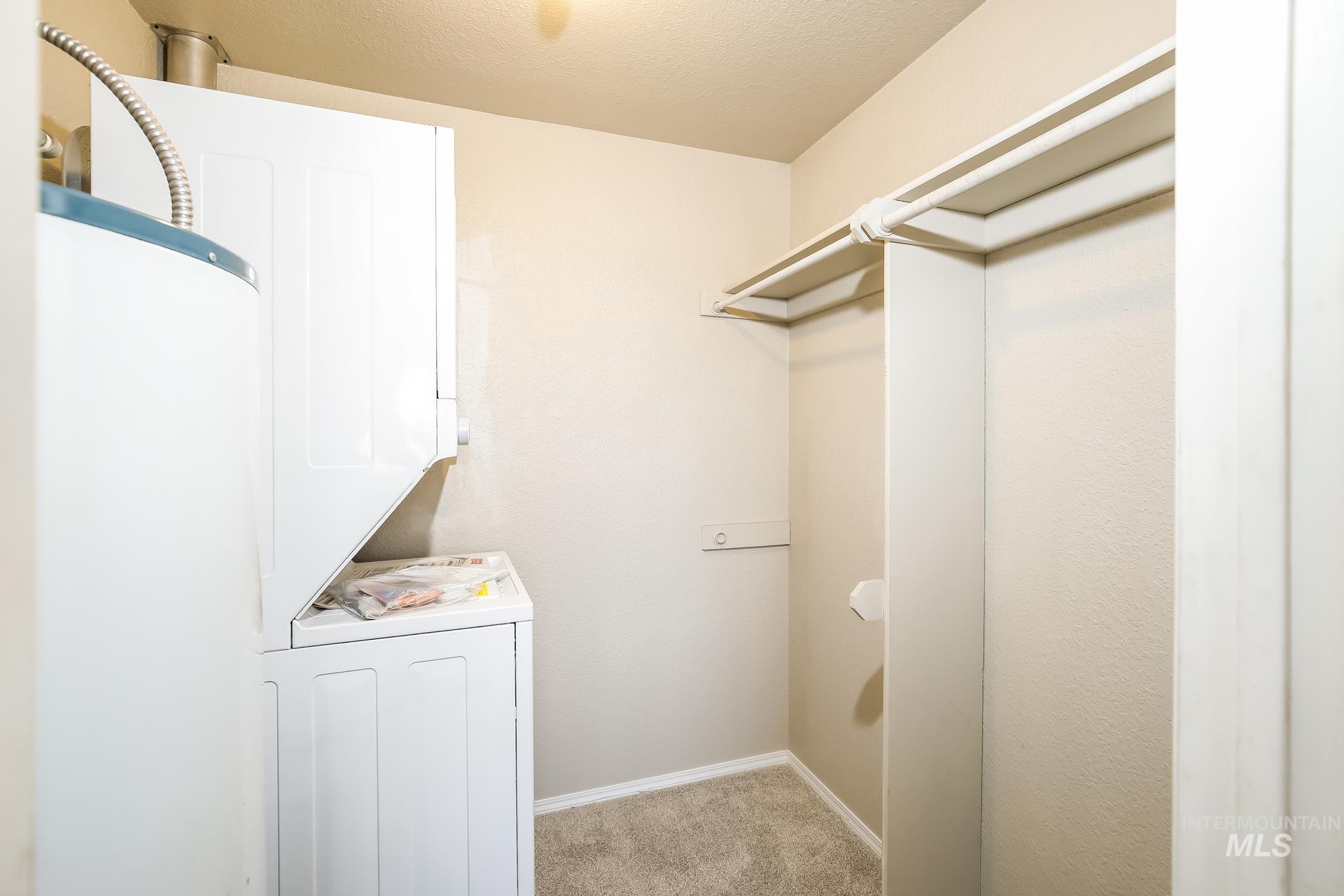 Walk in closet with light carpet and water heater