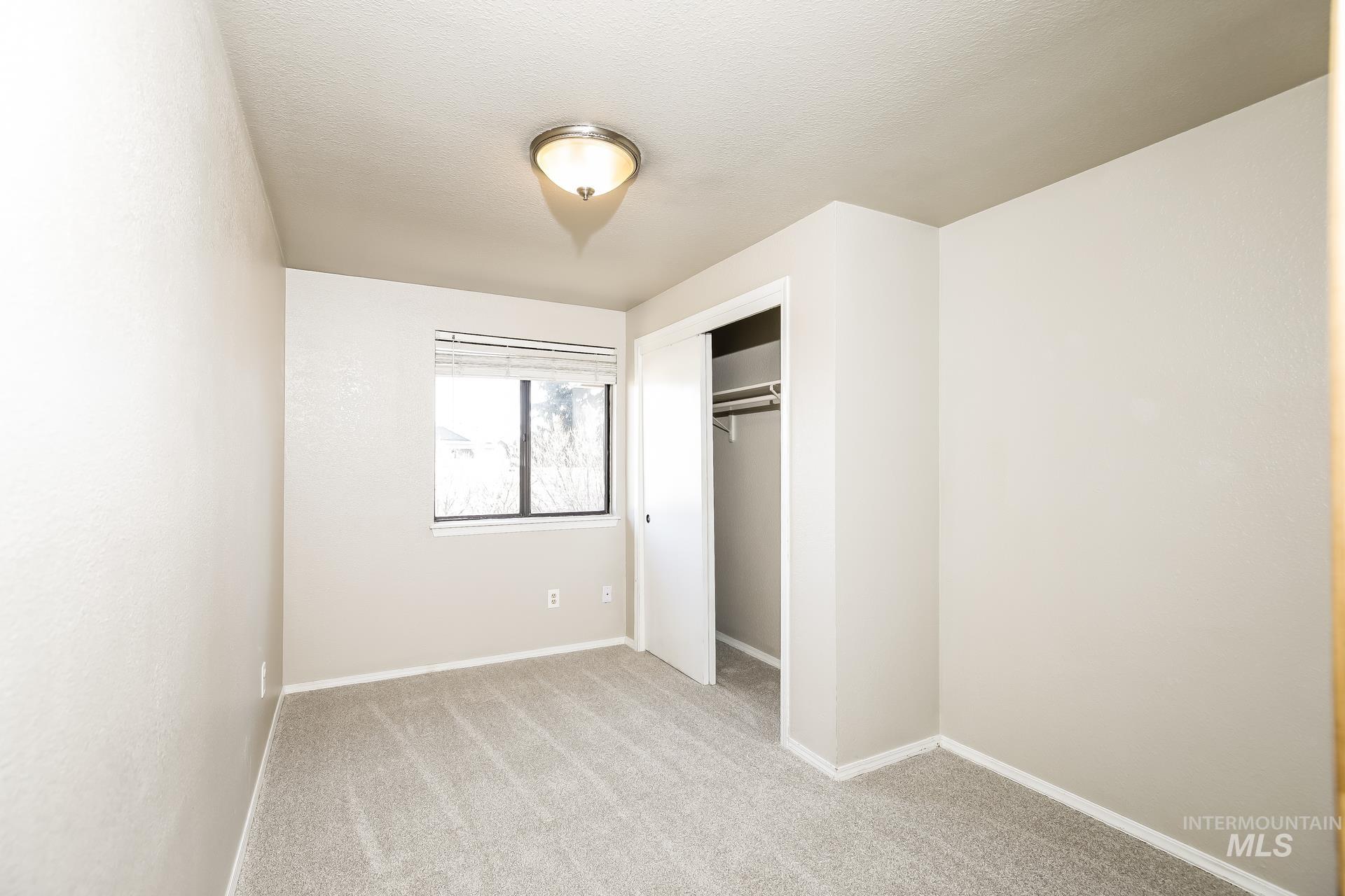 Unfurnished bedroom featuring light carpet and a closet