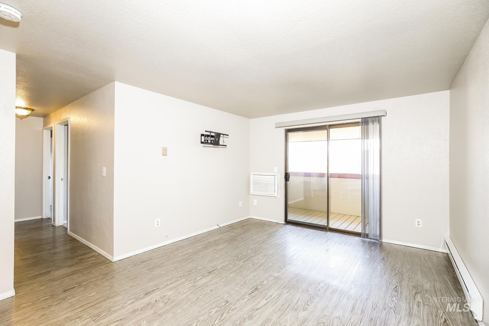 Spare room with a baseboard heating unit, light wood-style flooring, and a textured ceiling