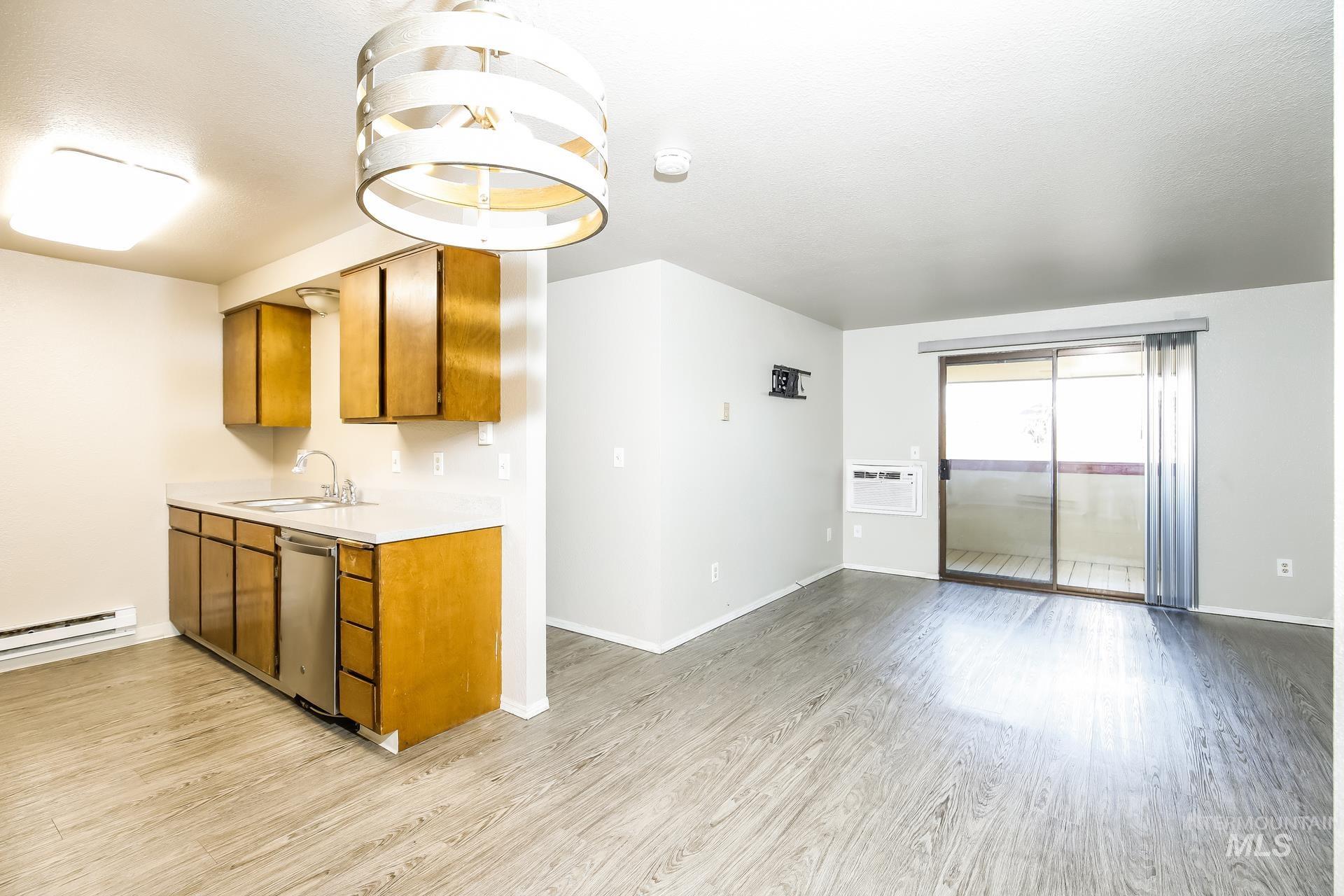 Kitchen featuring brown cabinetry, light countertops, light wood-style flooring, and stainless steel dishwasher