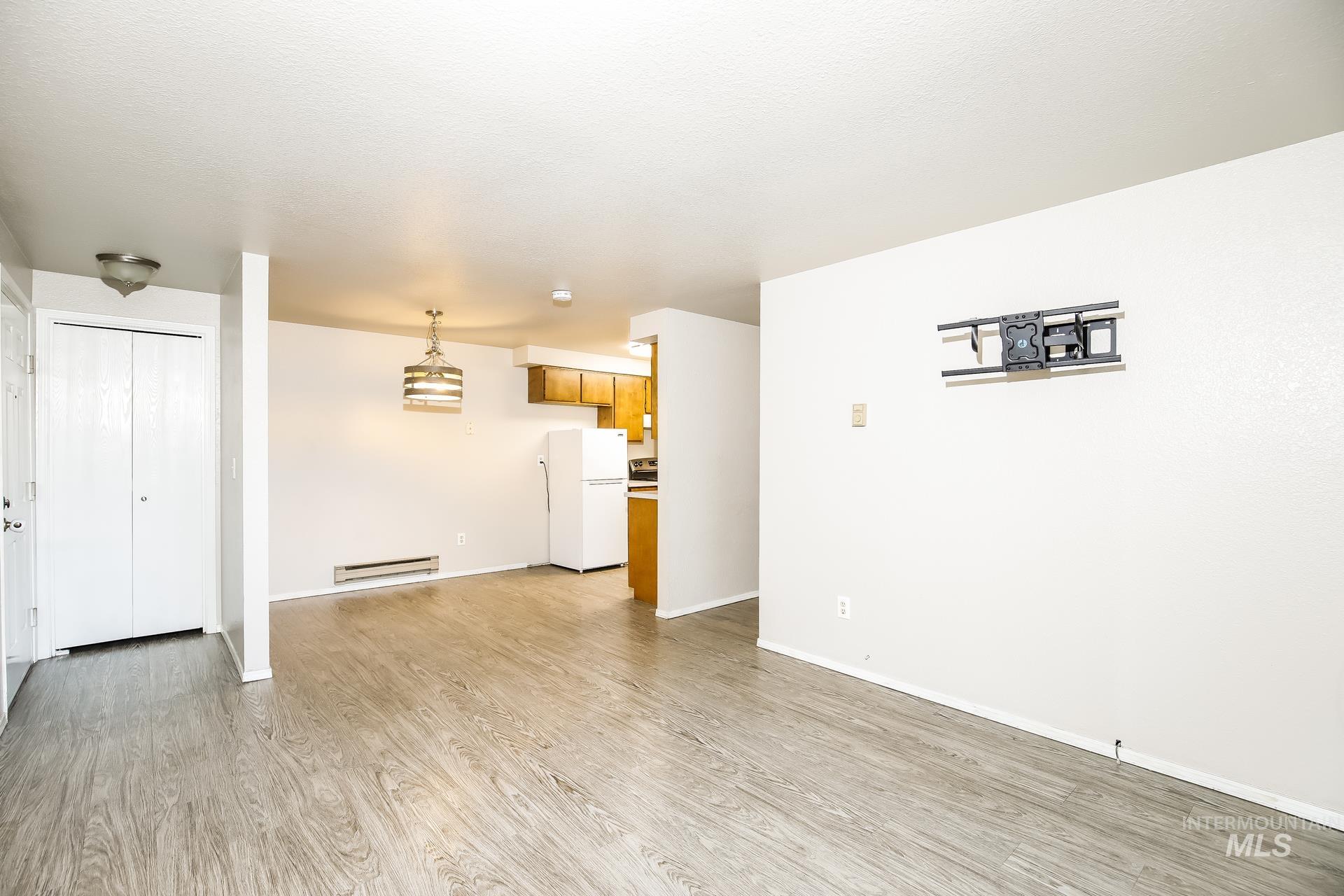 Unfurnished living room with light wood-style floors and a baseboard radiator