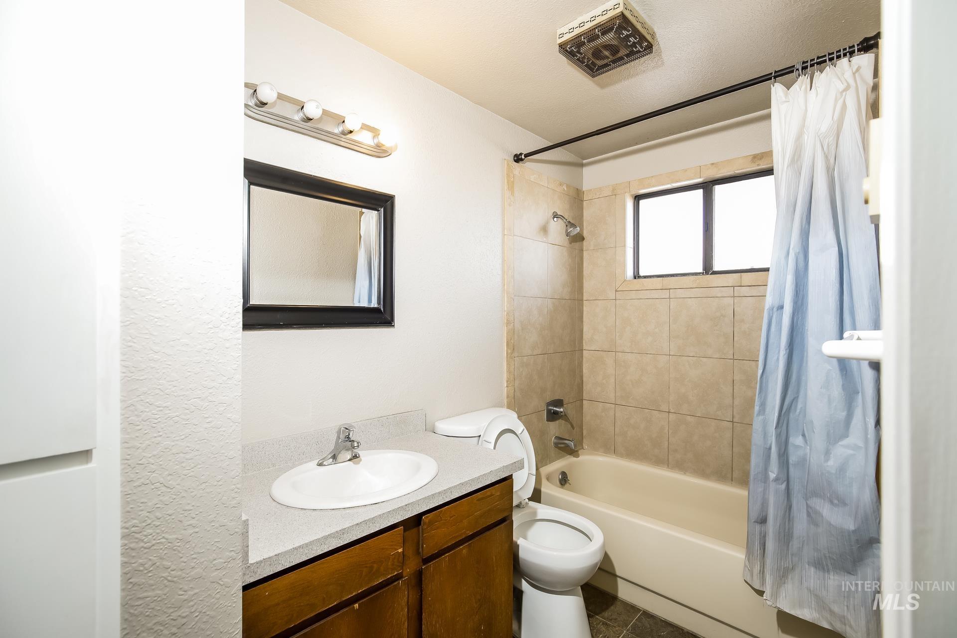 Full bath with shower / tub combo with curtain and vanity