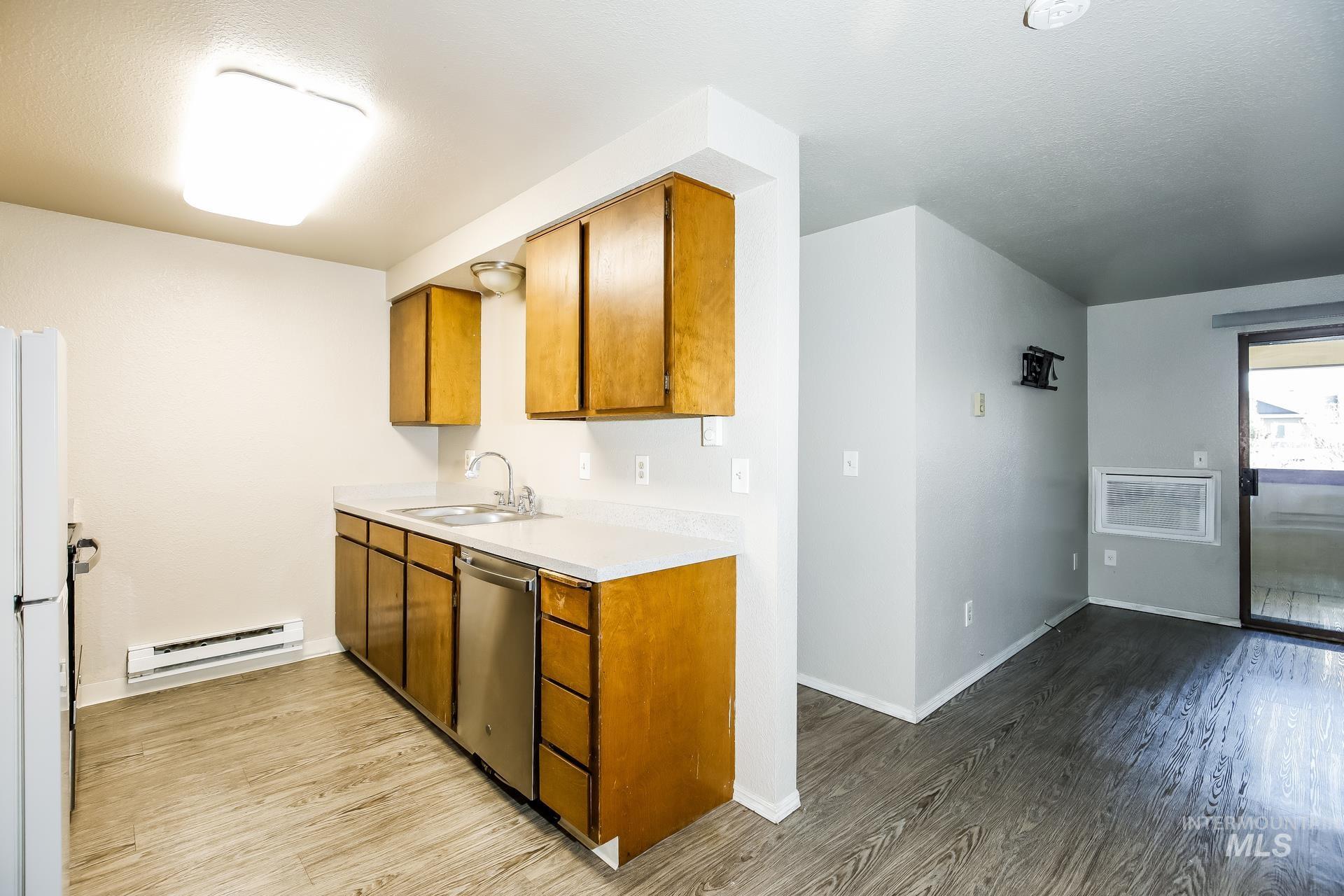 Kitchen with brown cabinetry, light countertops, light wood-style floors, and baseboard heating
