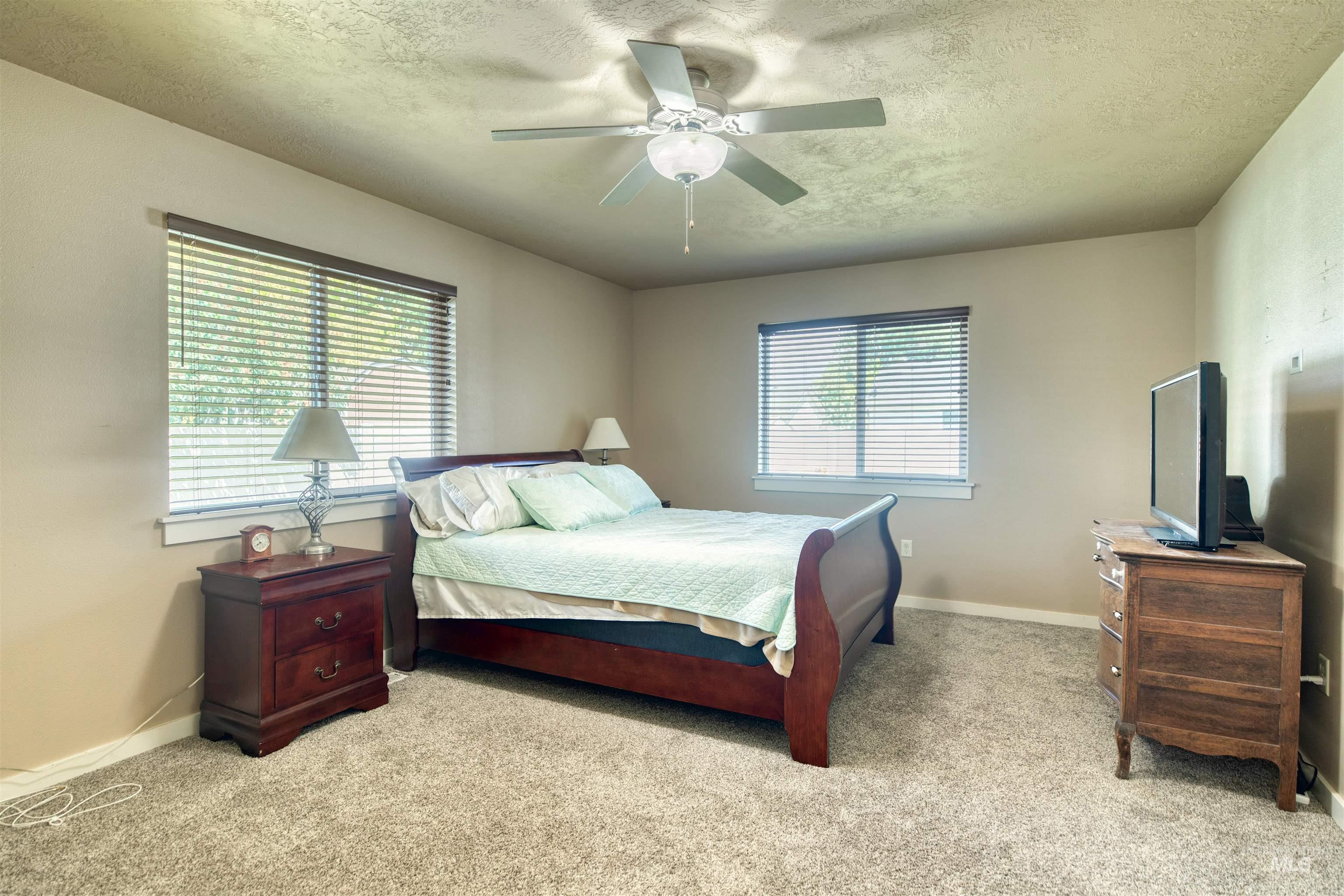Bedroom with carpet flooring, a textured ceiling, and a ceiling fan