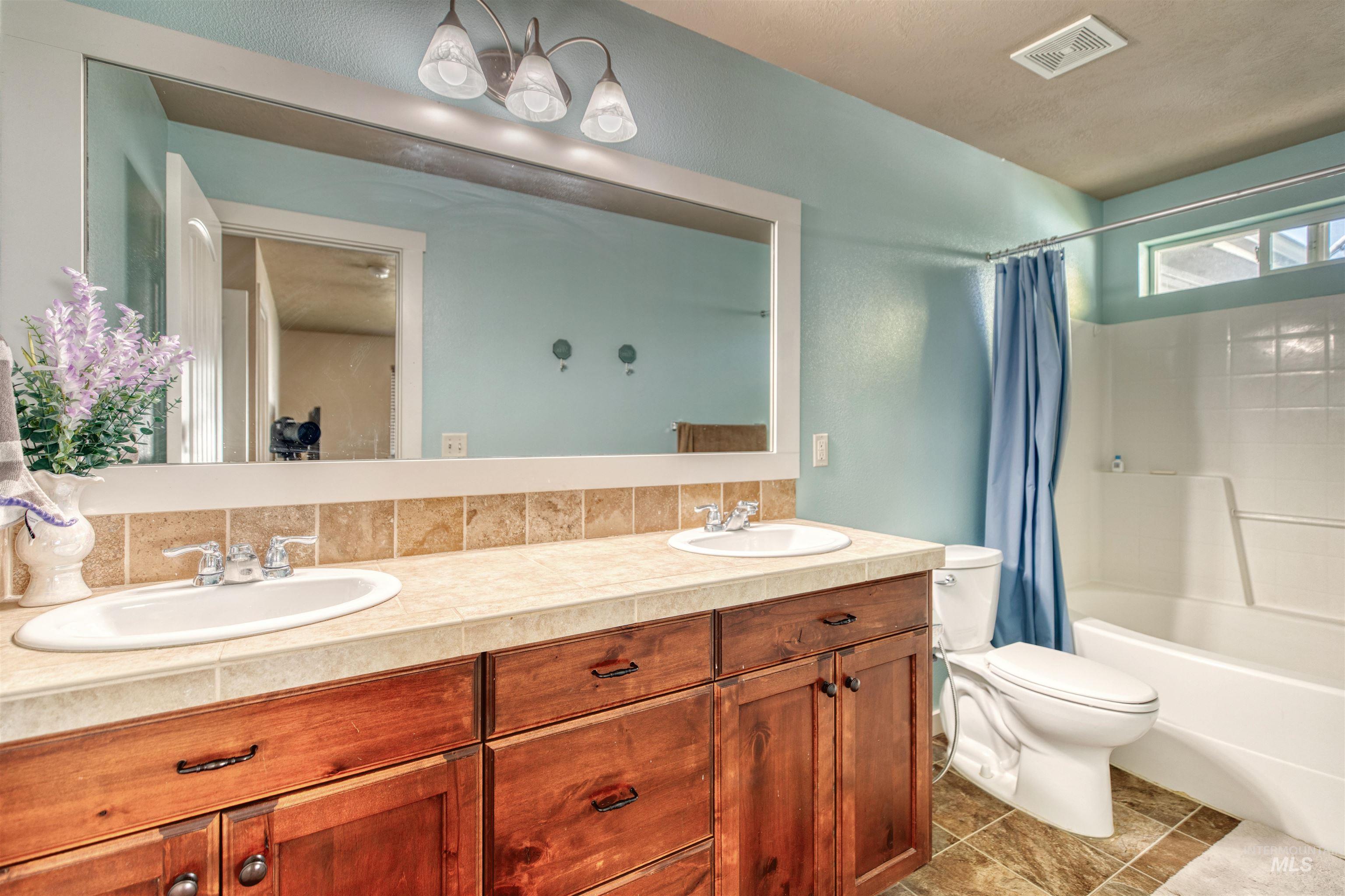 Bathroom with double vanity and shower / bath combination with curtain