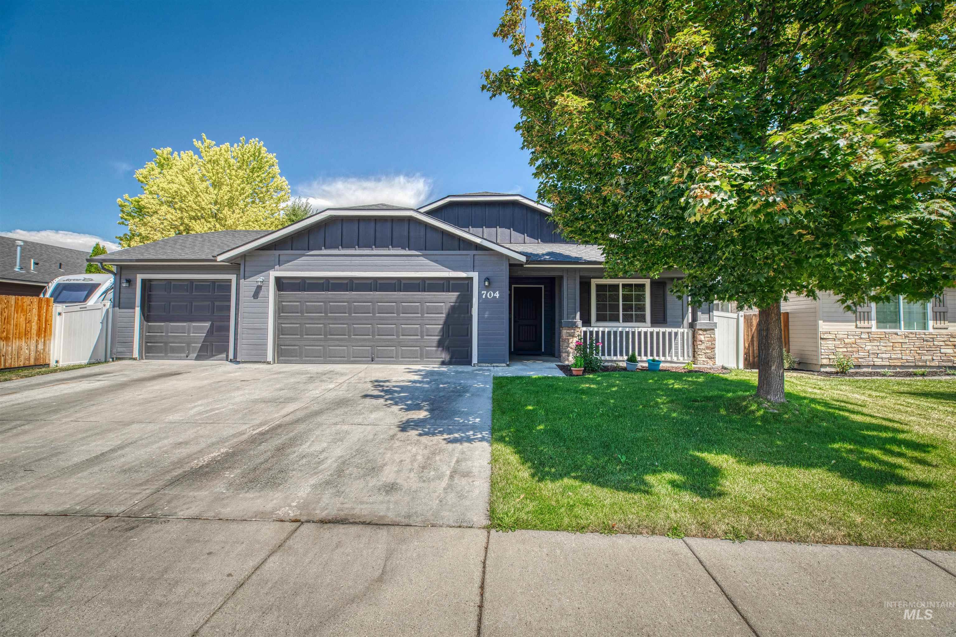 View of front of house featuring an attached garage, concrete driveway, covered porch, stone siding, and board and batten siding