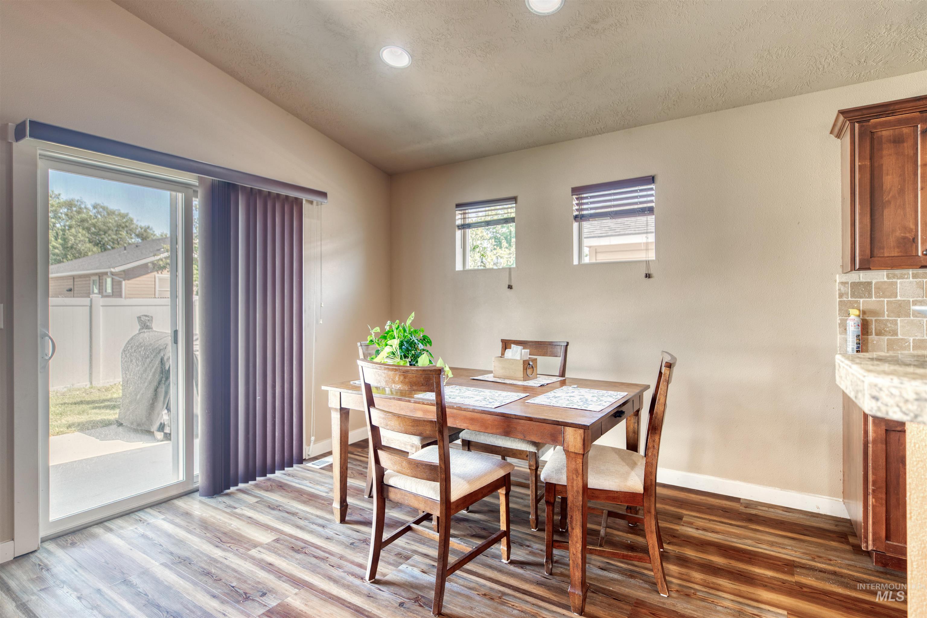 Dining room featuring light wood finished floors, vaulted ceiling, a textured ceiling, and recessed lighting
