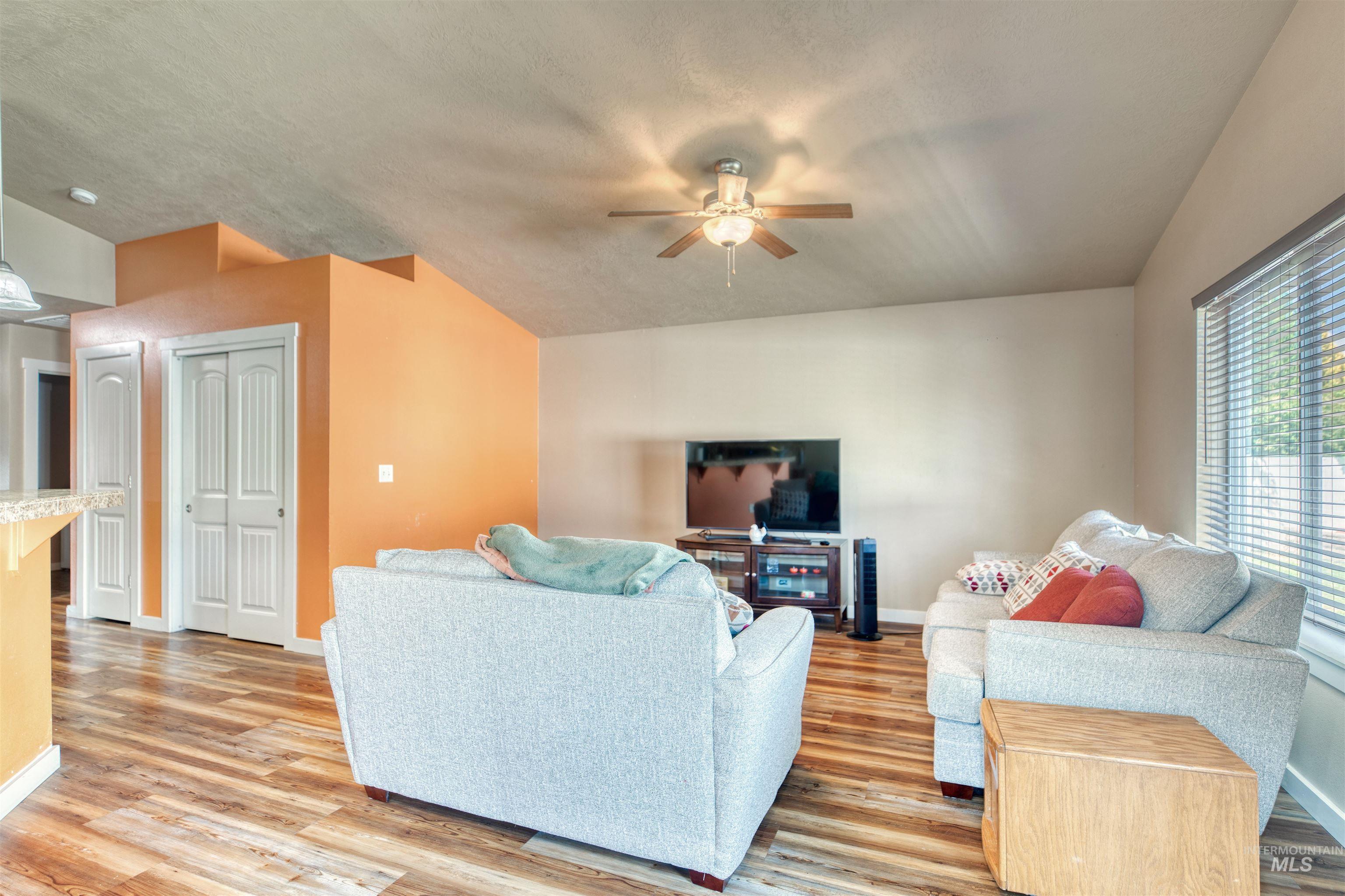 Living area featuring a ceiling fan, light wood-style flooring, and a textured ceiling