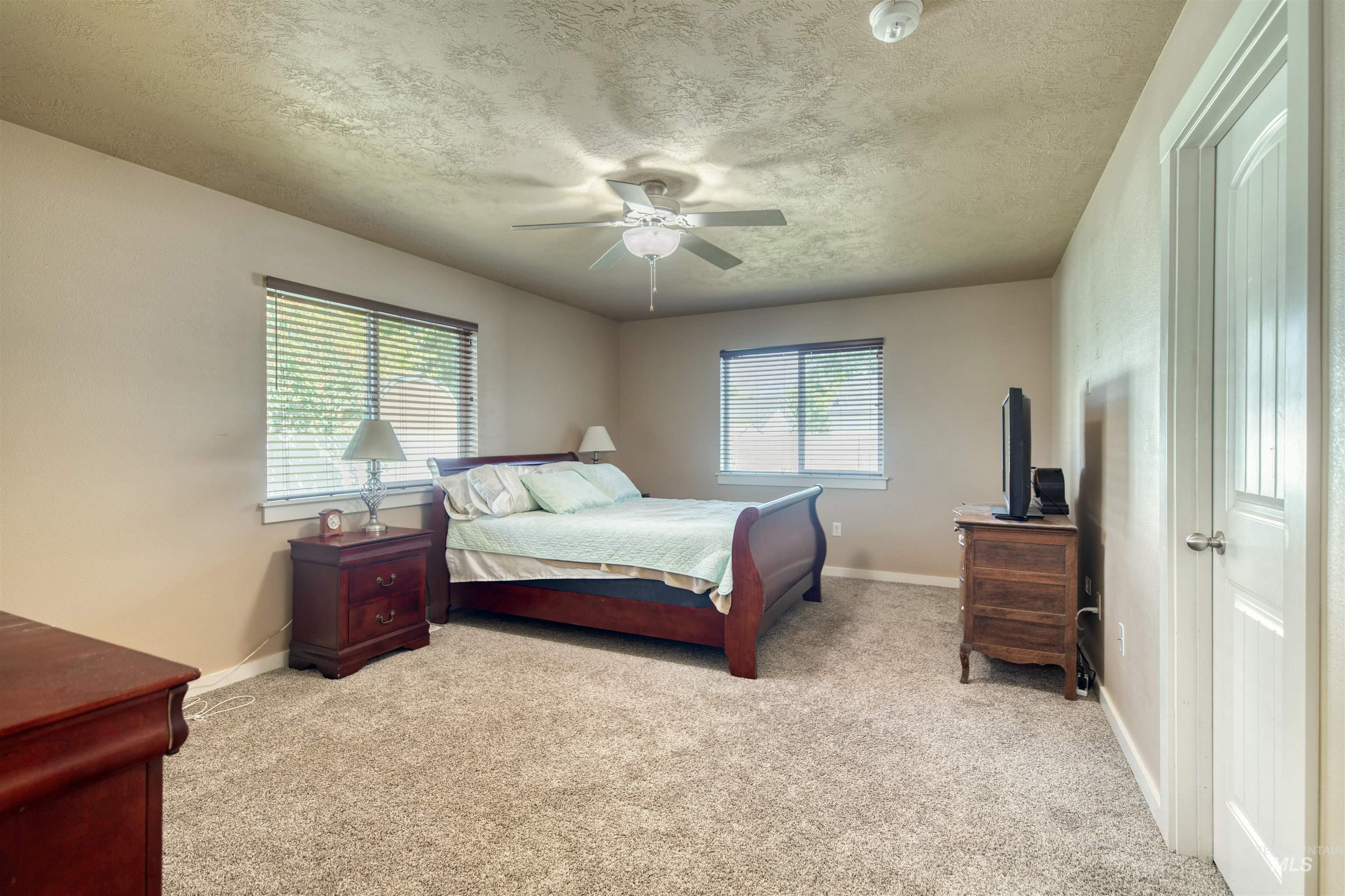 Bedroom featuring carpet, a textured ceiling, and ceiling fan
